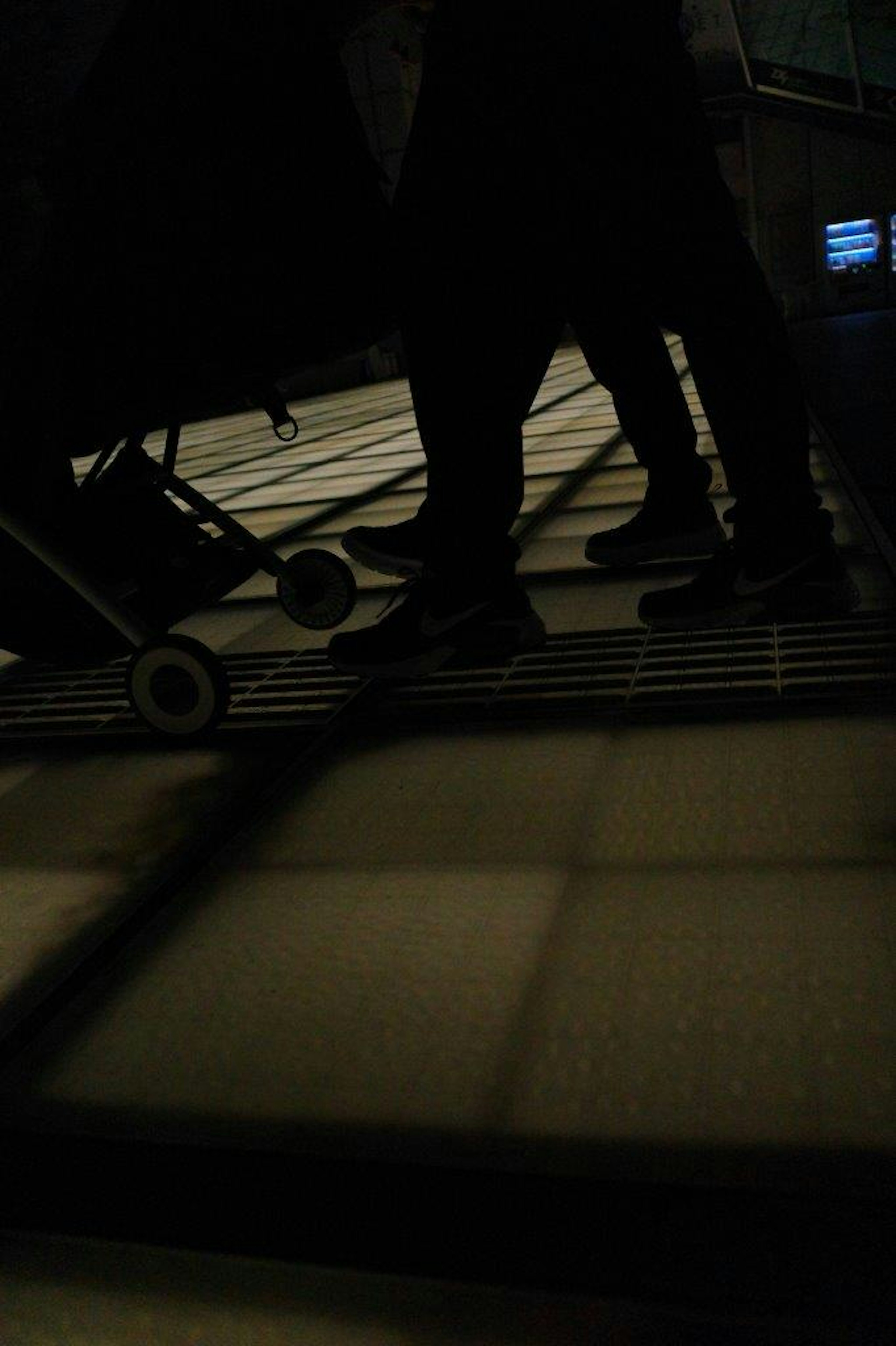 Low angle view of people's feet and a cart wheel casting shadows