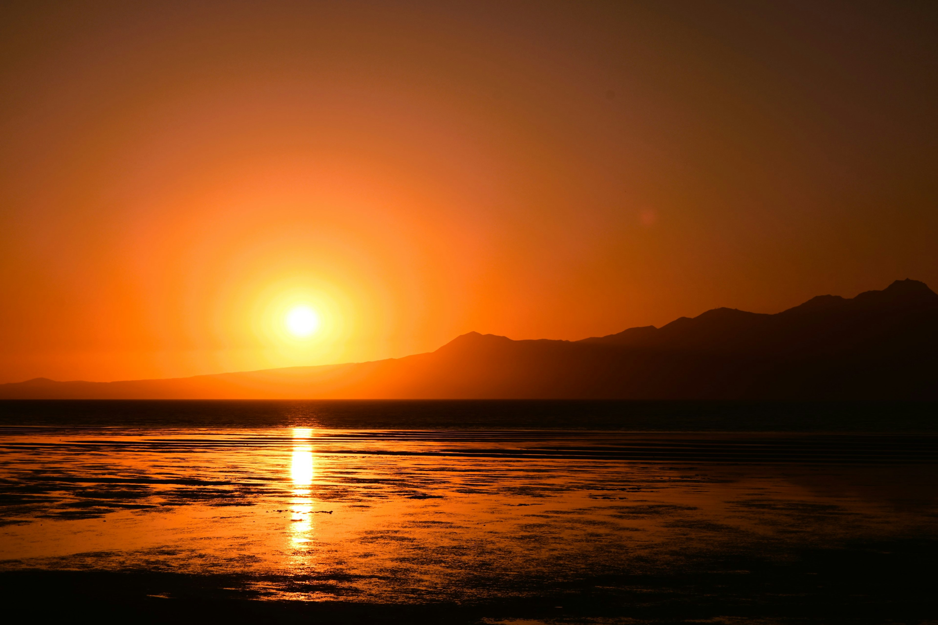 美しいオレンジ色の夕日が山の背後に沈む様子