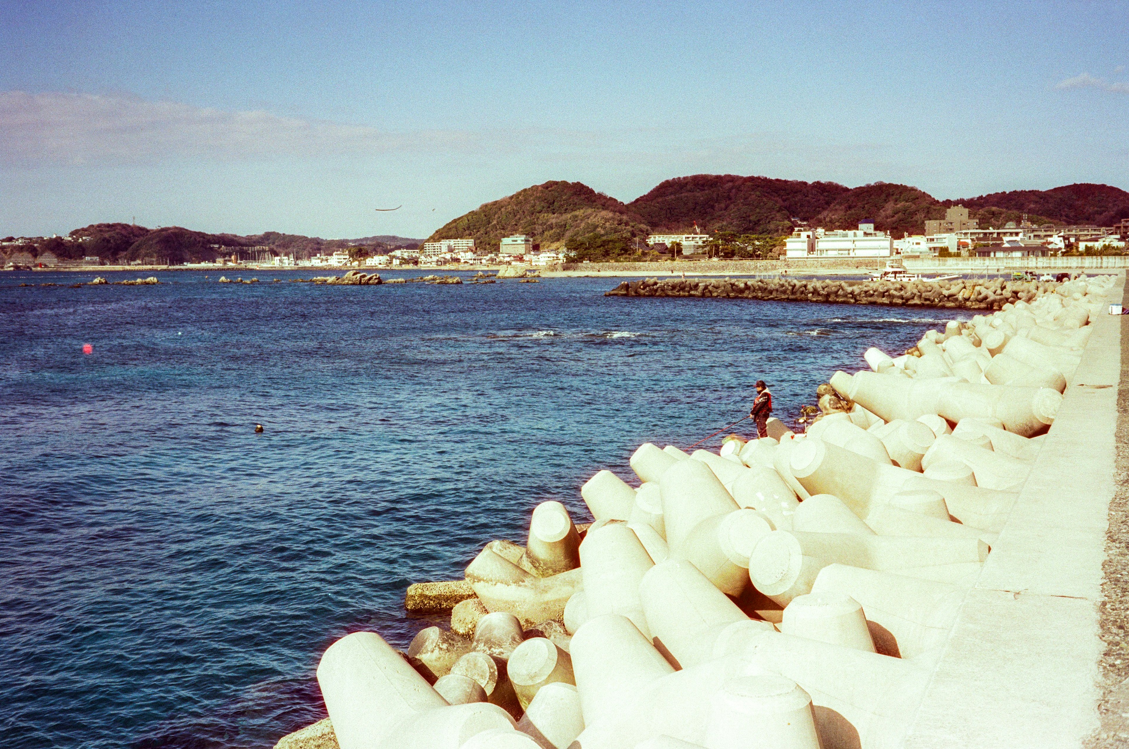 Scenic view of blue sea with white breakwater a person standing near the breakwater