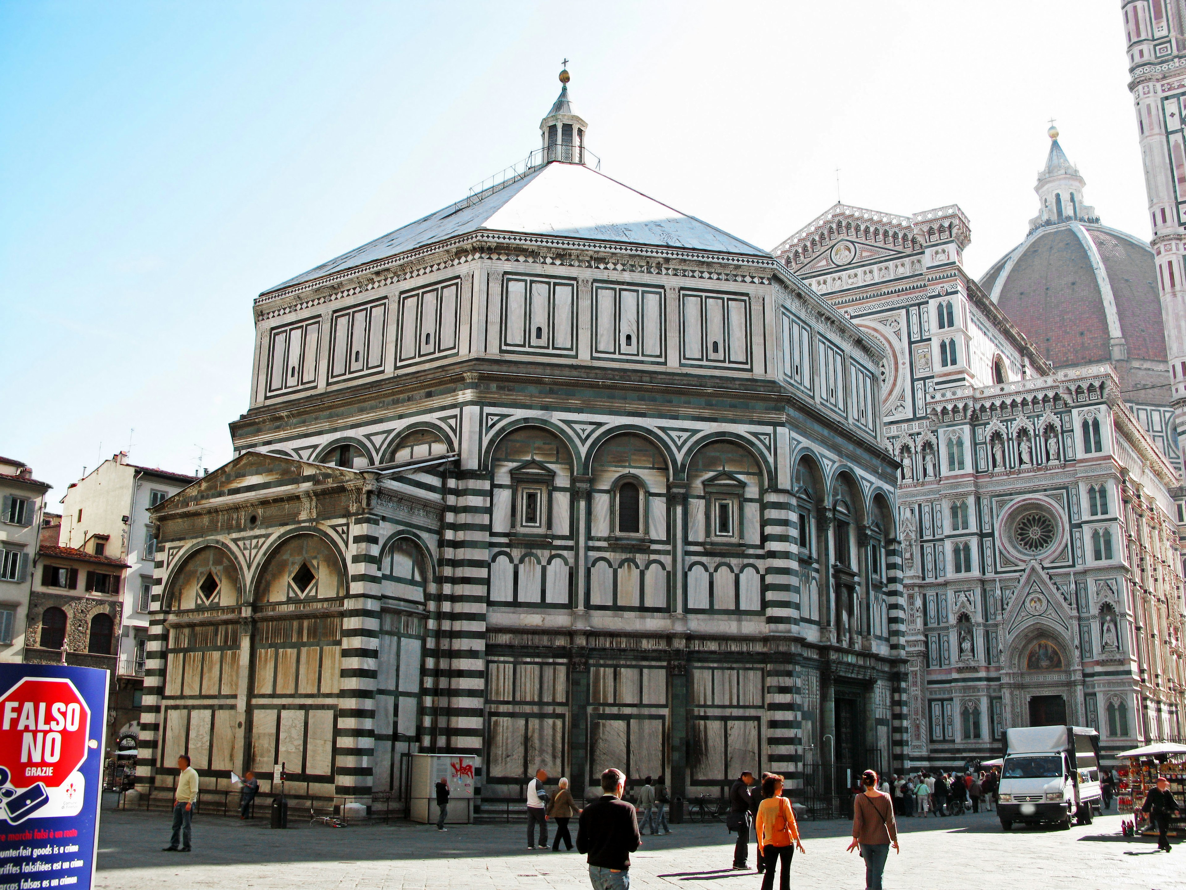 Exterior view of the Baptistery of Florence with people walking nearby