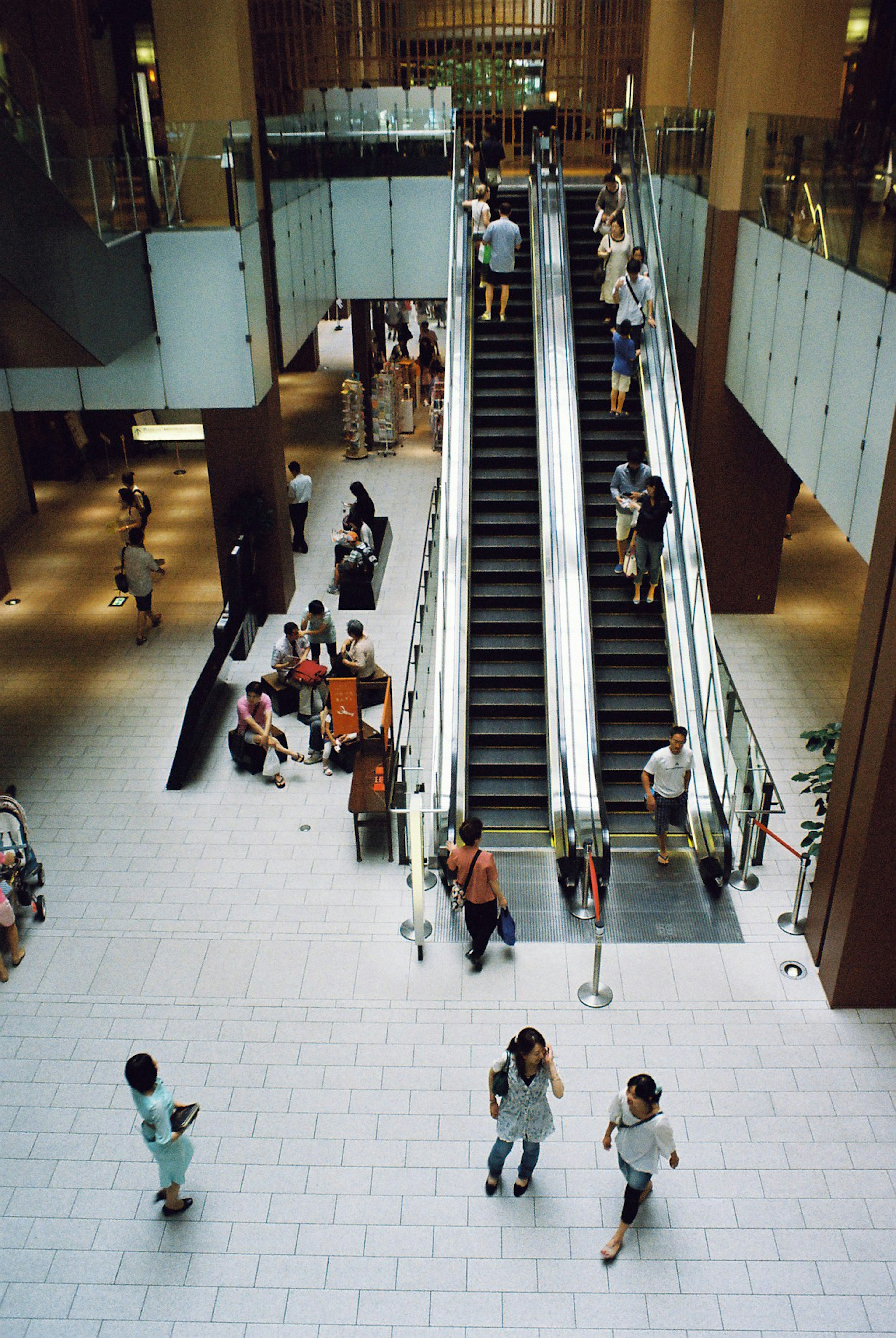 Innenansicht eines modernen Einkaufszentrums mit Rolltreppen und Menschen