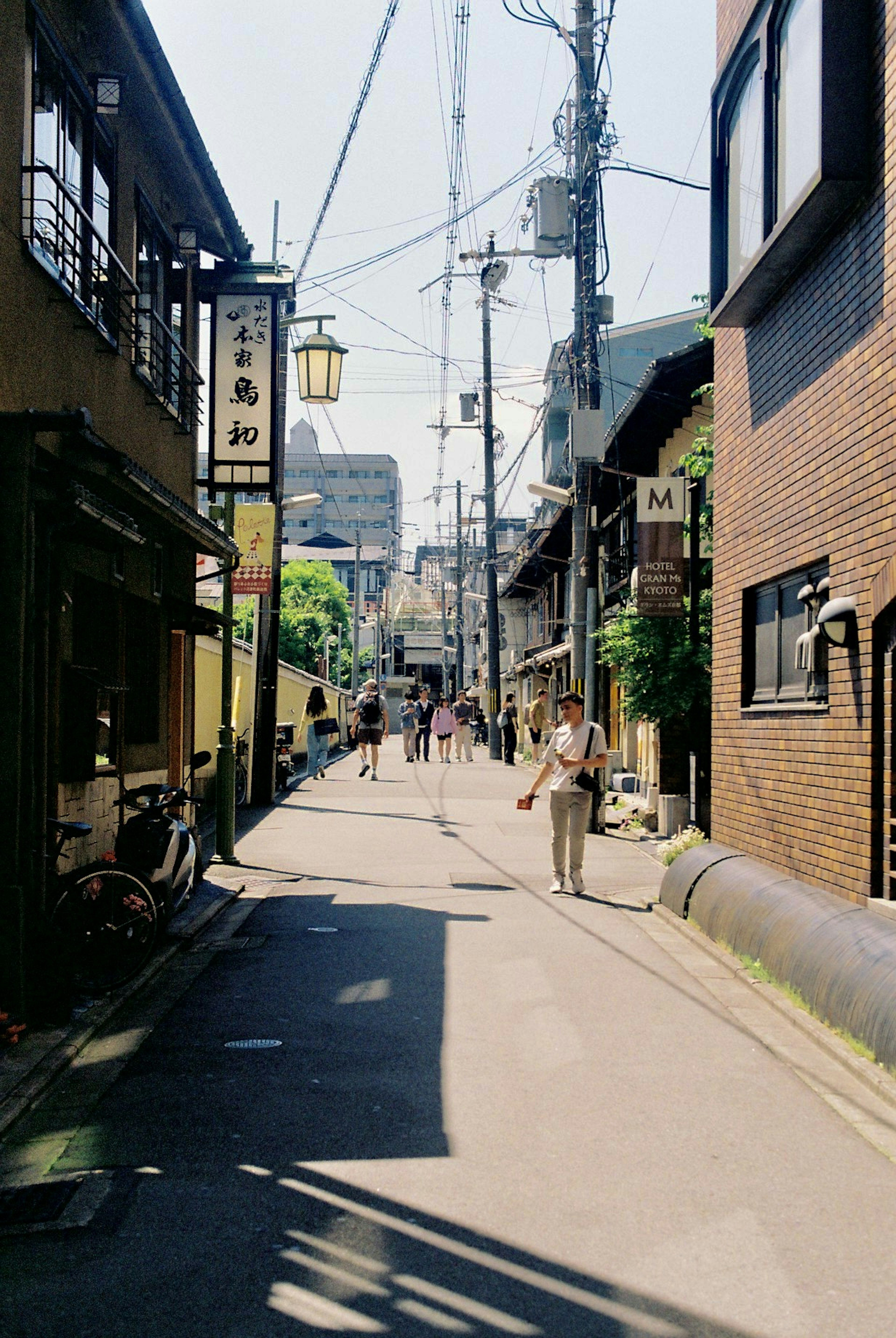 Calle estrecha flanqueada por edificios japoneses tradicionales y personas