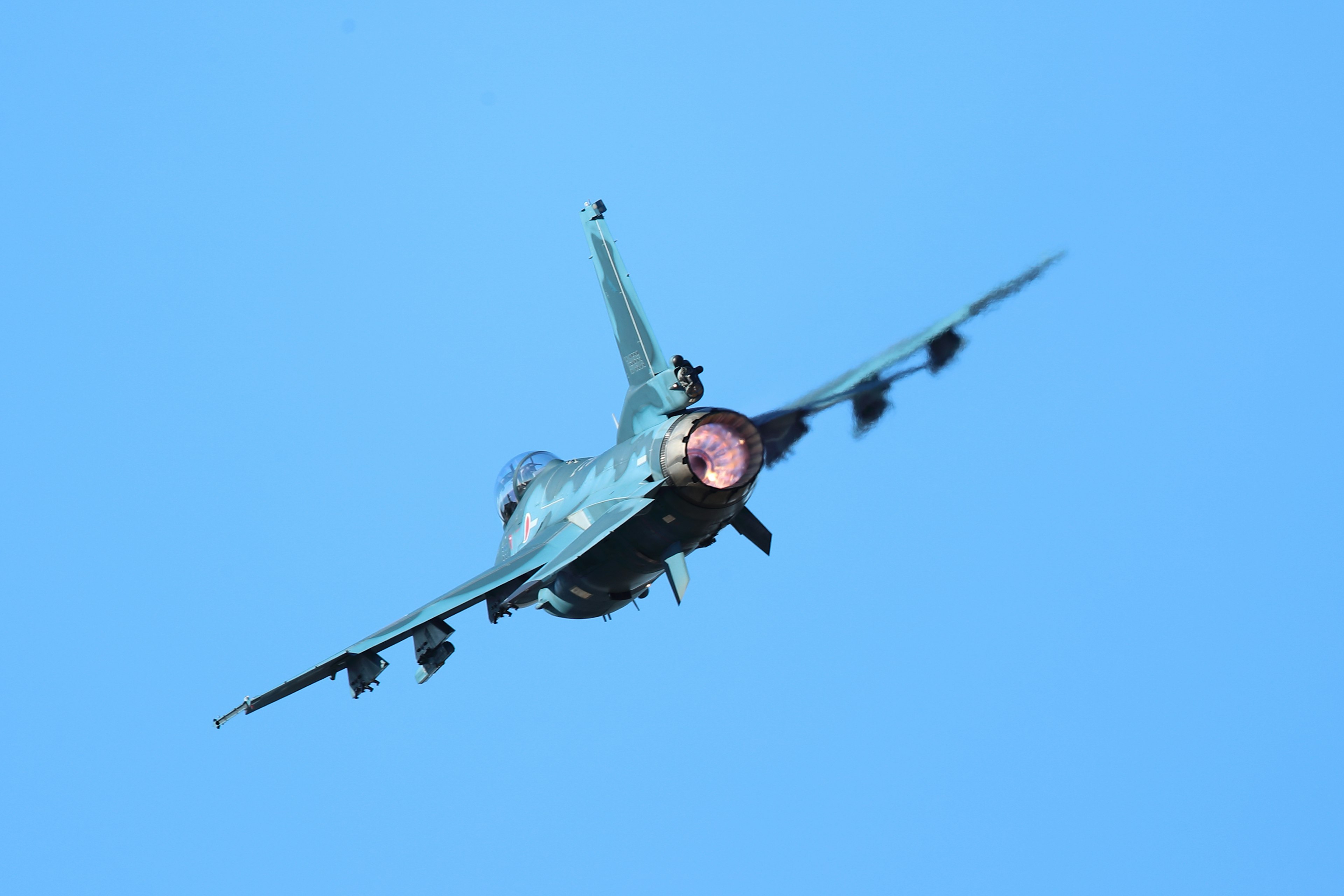 Fighter jet making a sharp turn against a blue sky