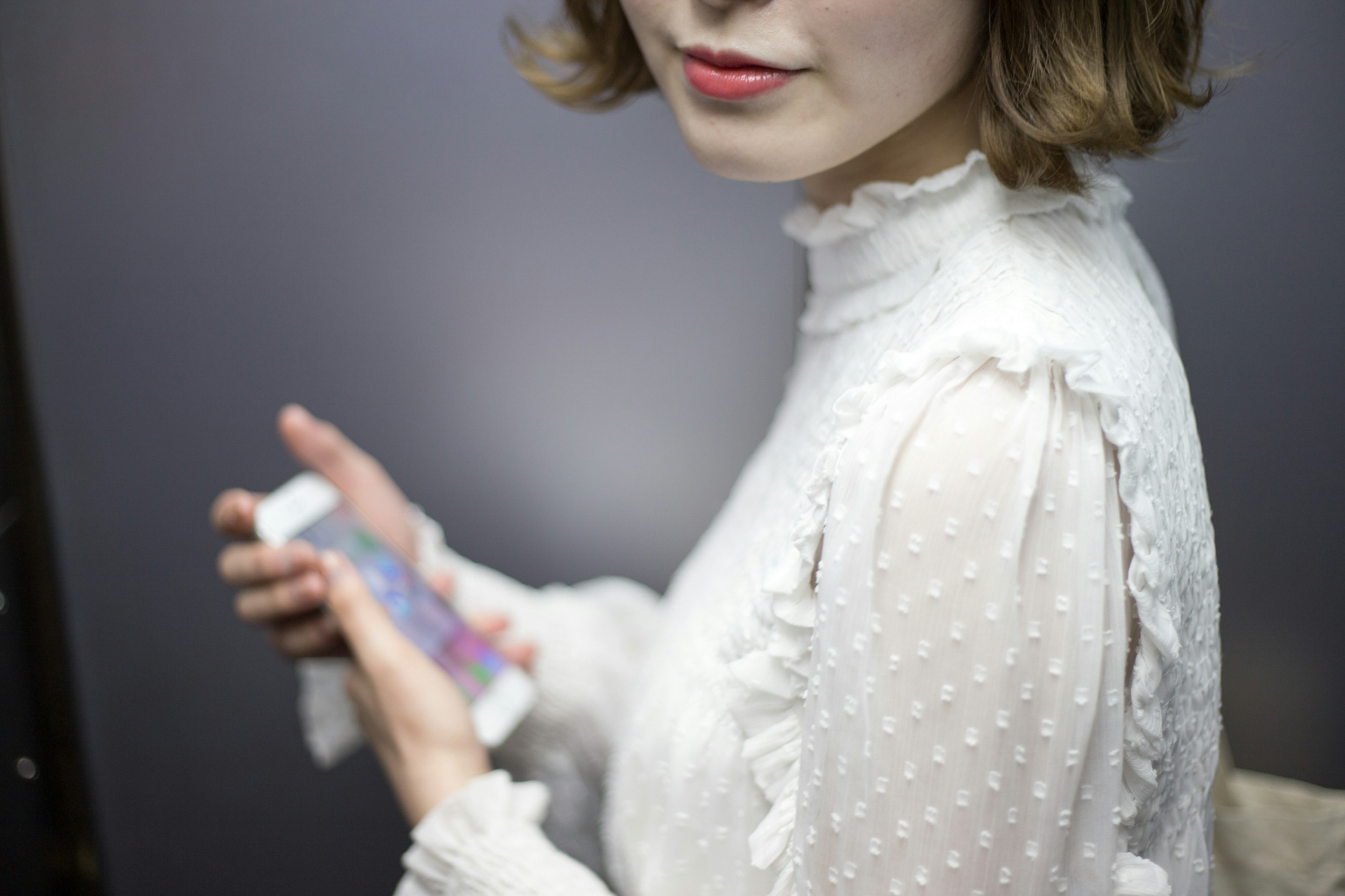 Woman in a white blouse holding a smartphone