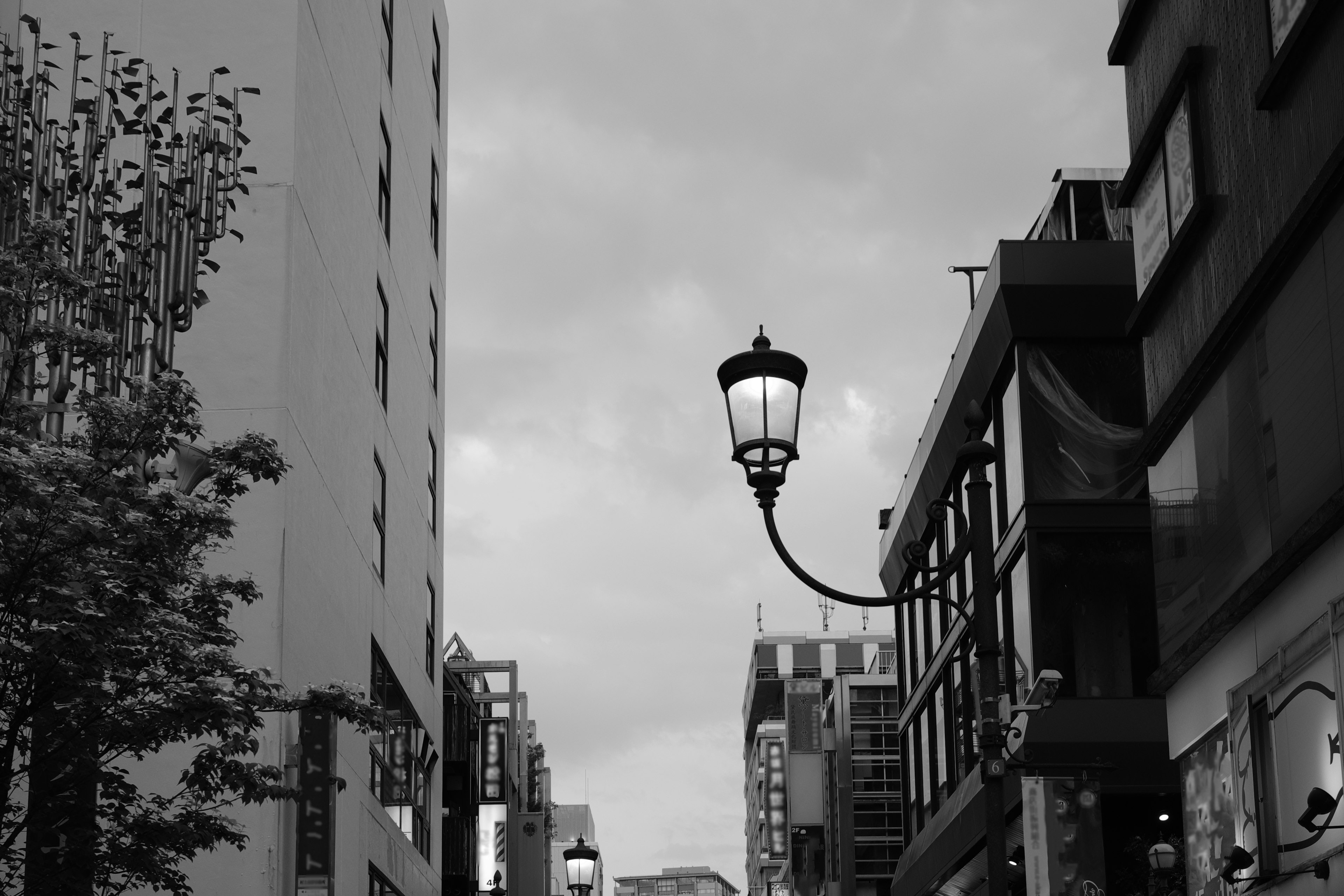 Pemandangan jalan hitam putih dengan lampu jalan vintage dan bangunan modern