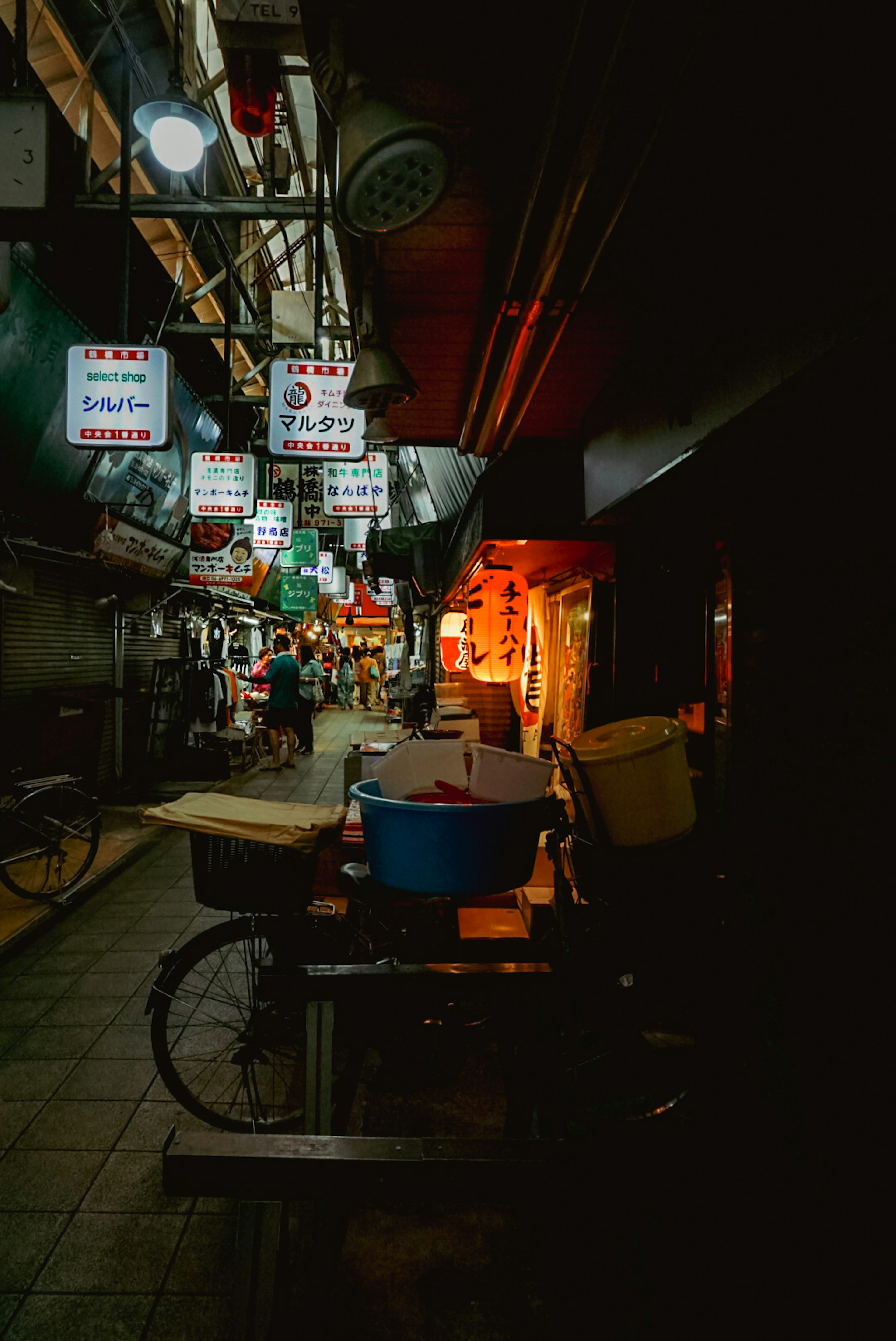 暗い路地に並ぶ看板と自転車のある風景