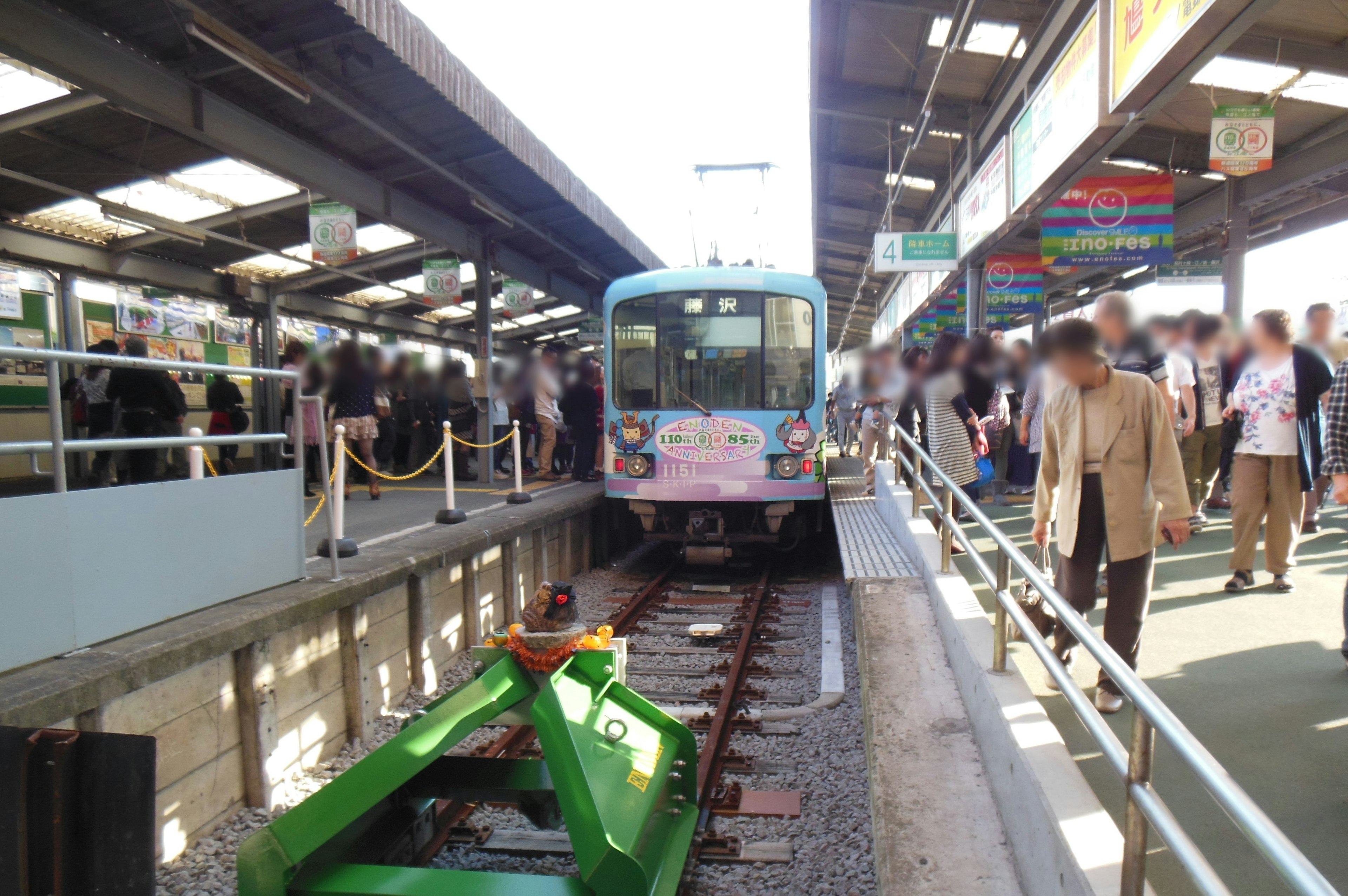 駅で待機中の青い電車と混雑したプラットフォーム