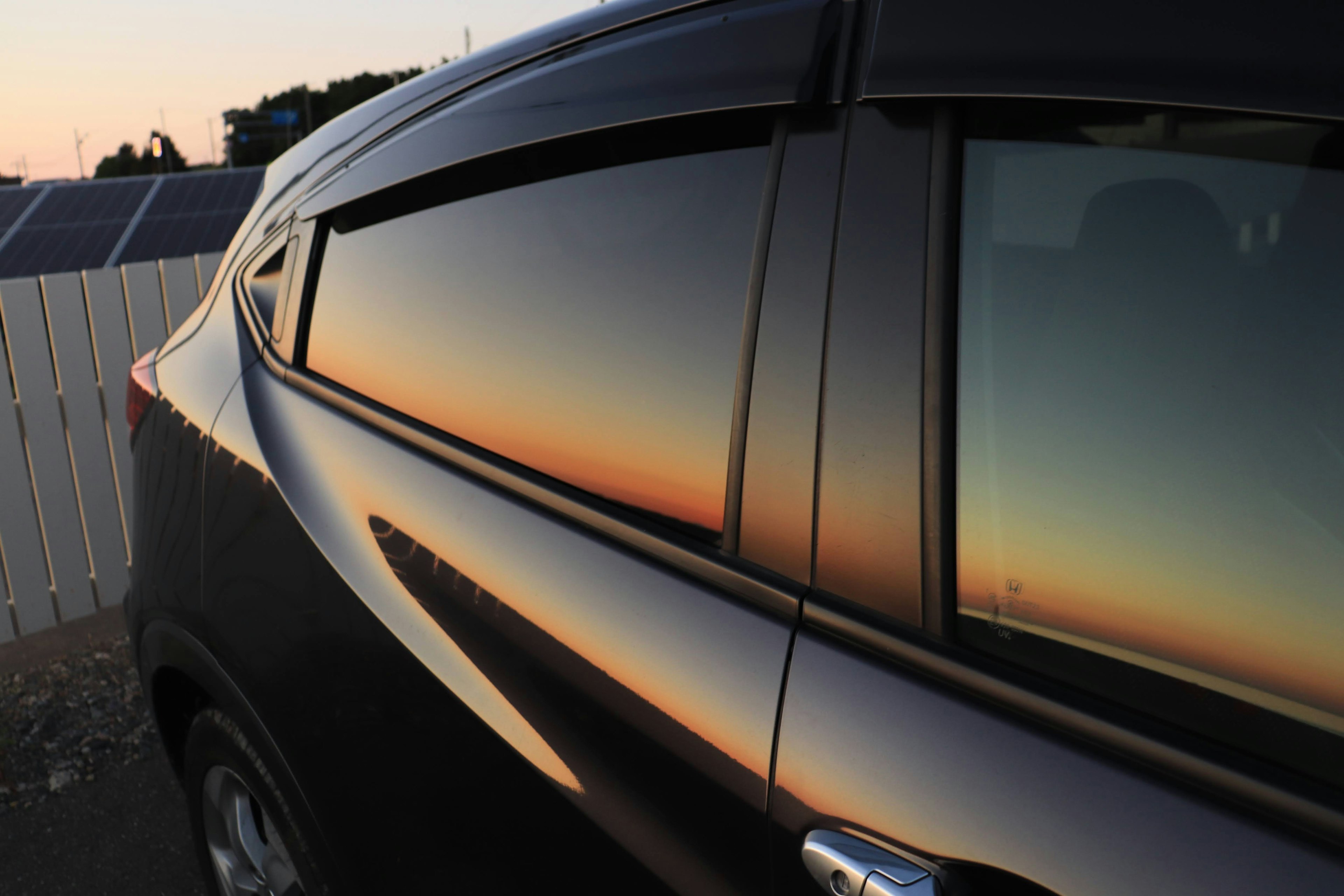 Reflexion des Sonnenuntergangsverlaufs auf einem schwarzen Autofenster