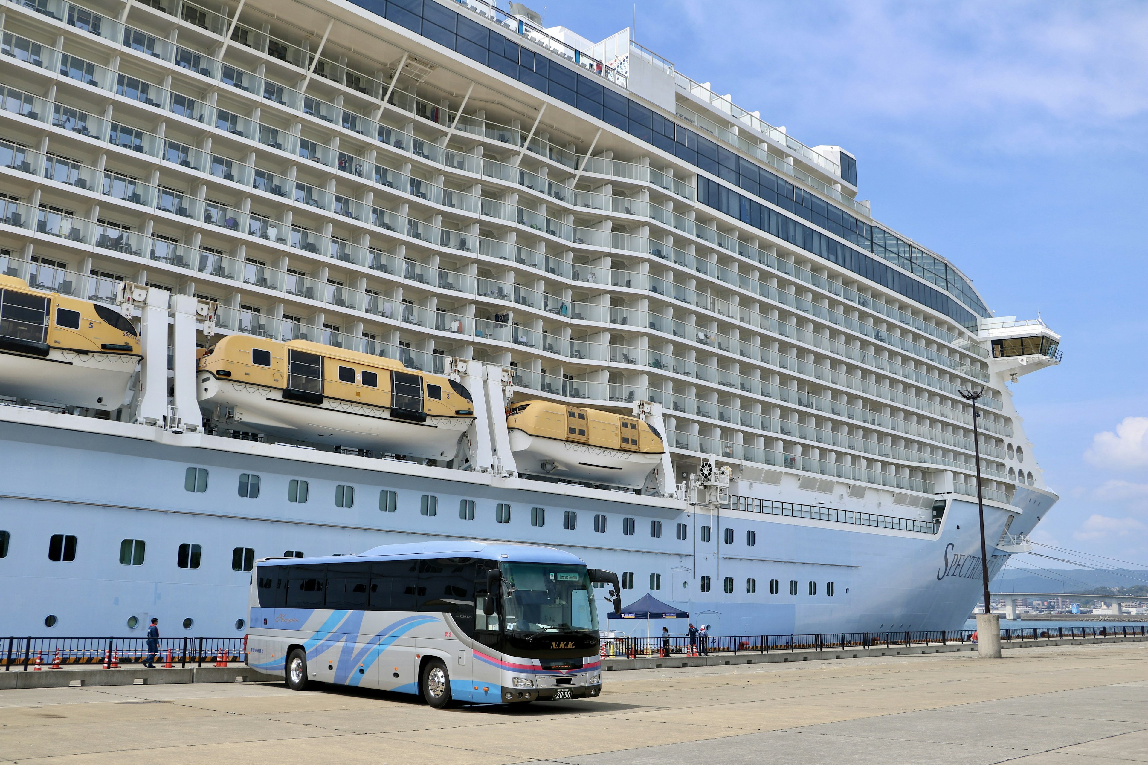 Vue latérale d'un grand navire de croisière avec un bus garé à proximité