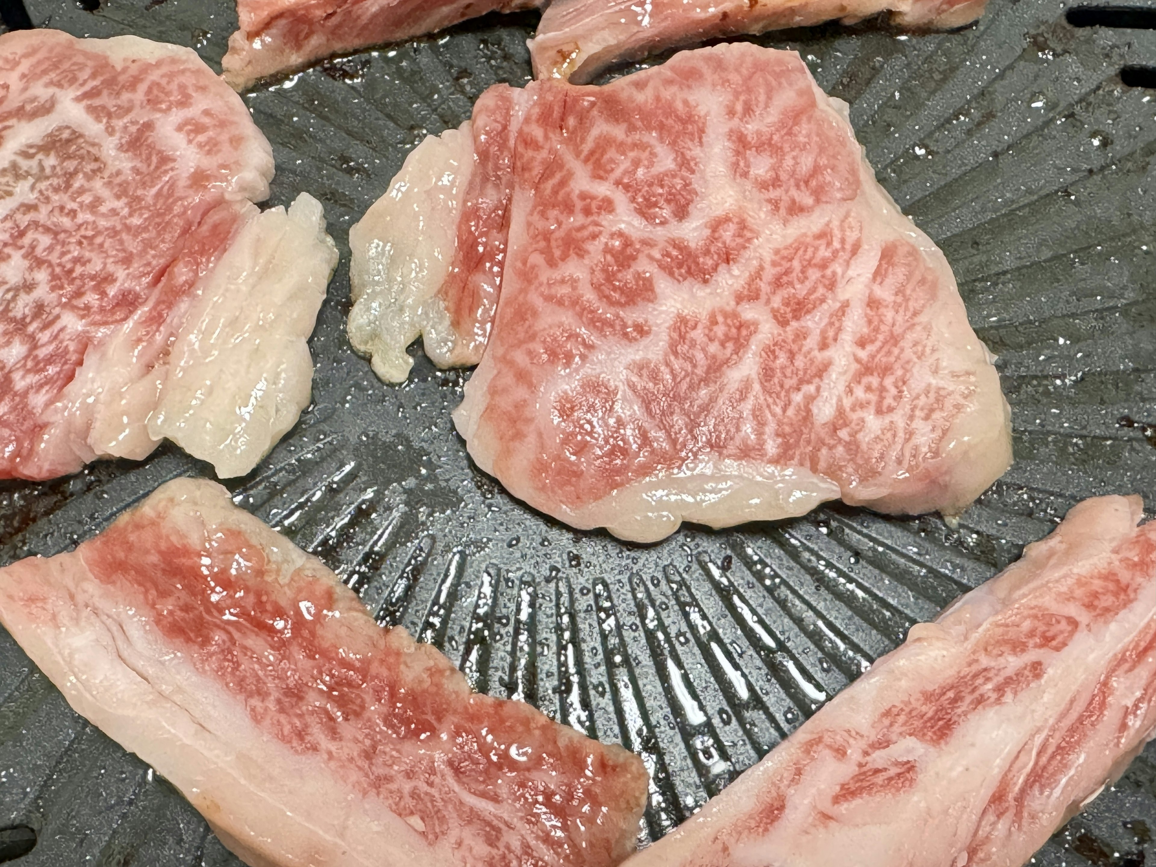 Sliced wagyu beef arranged on a grill