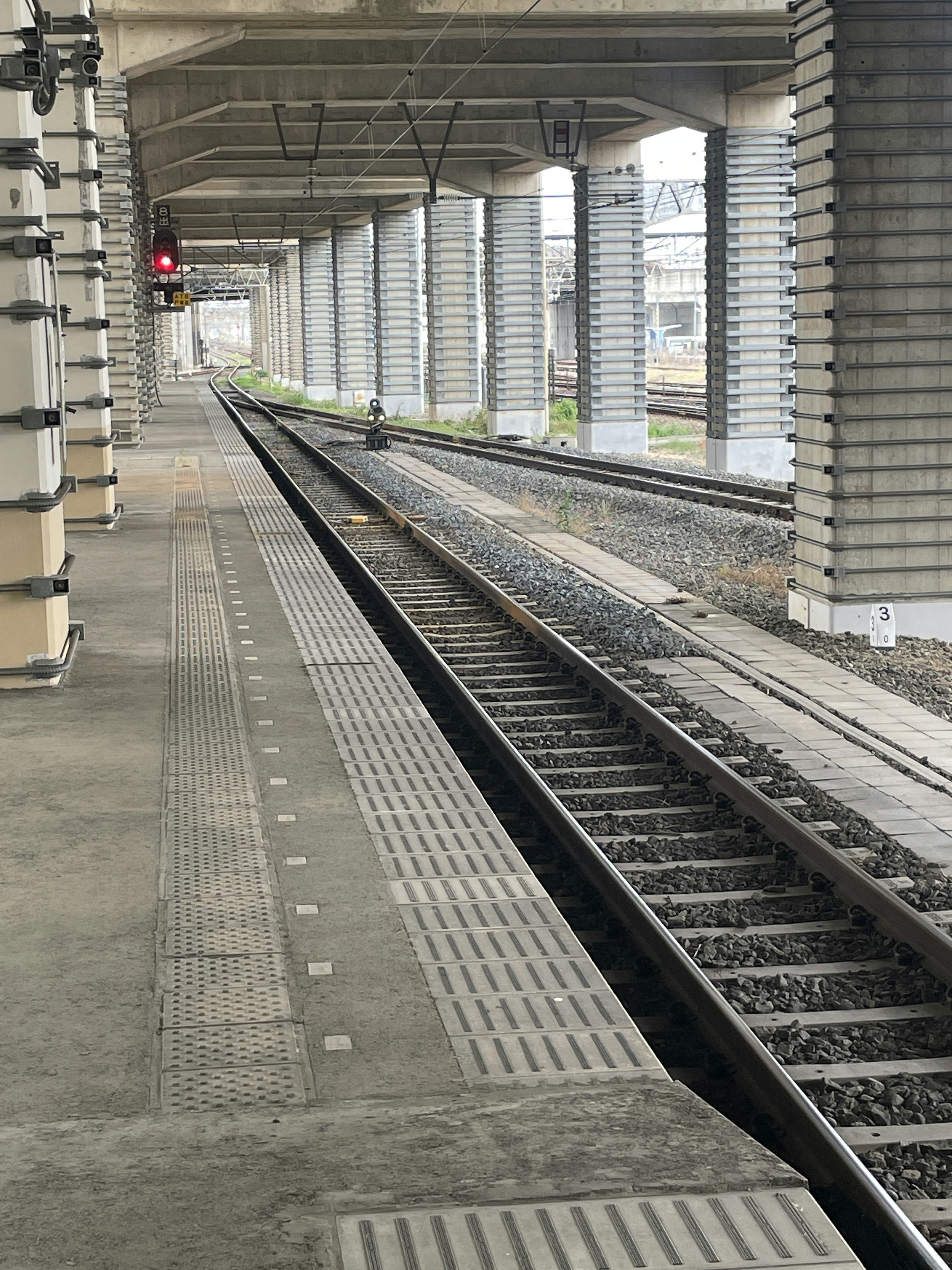 Platform view with railway tracks and a lit red signal