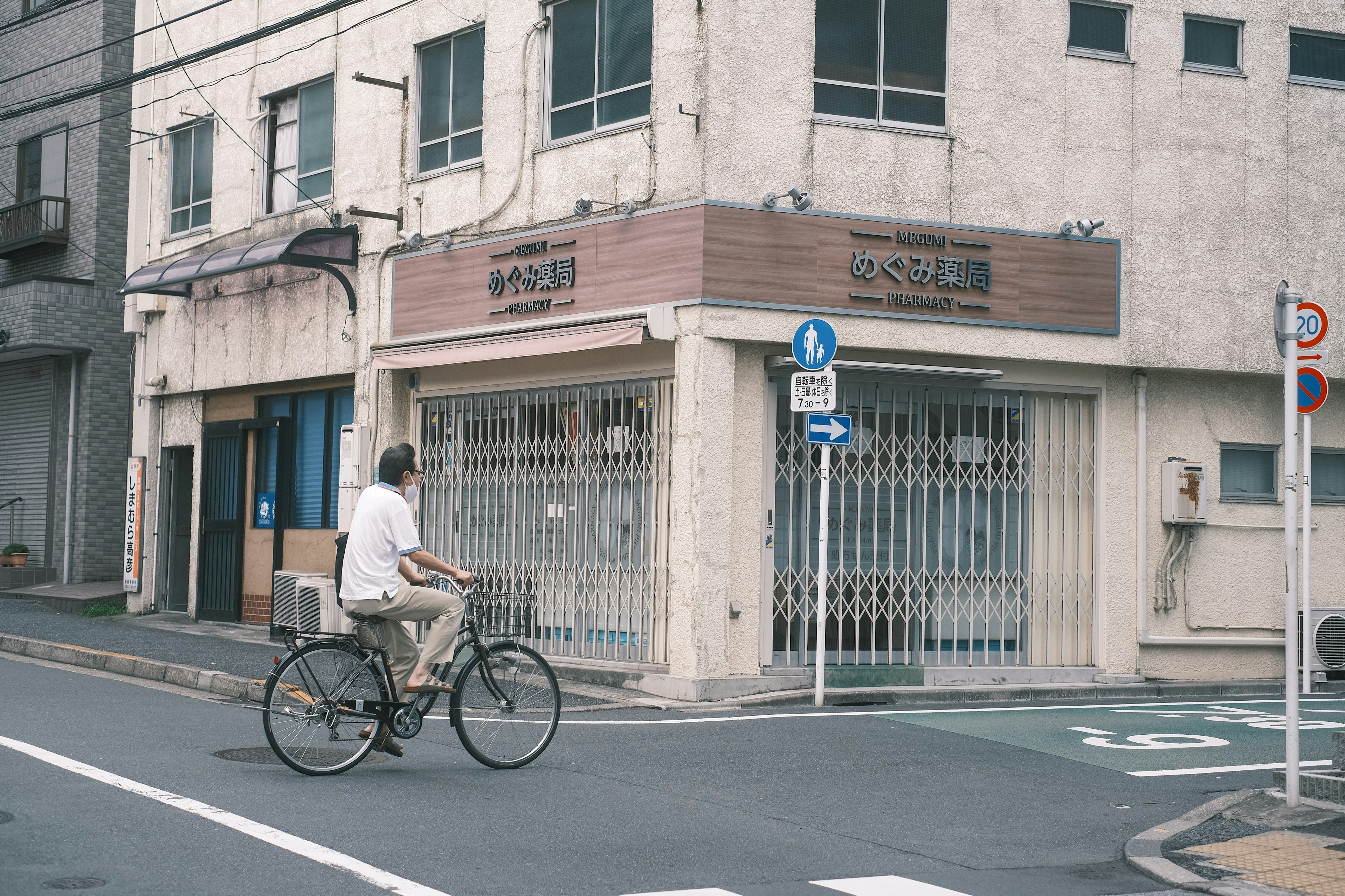 自転車に乗る男性と閉じた店舗のある静かな街角