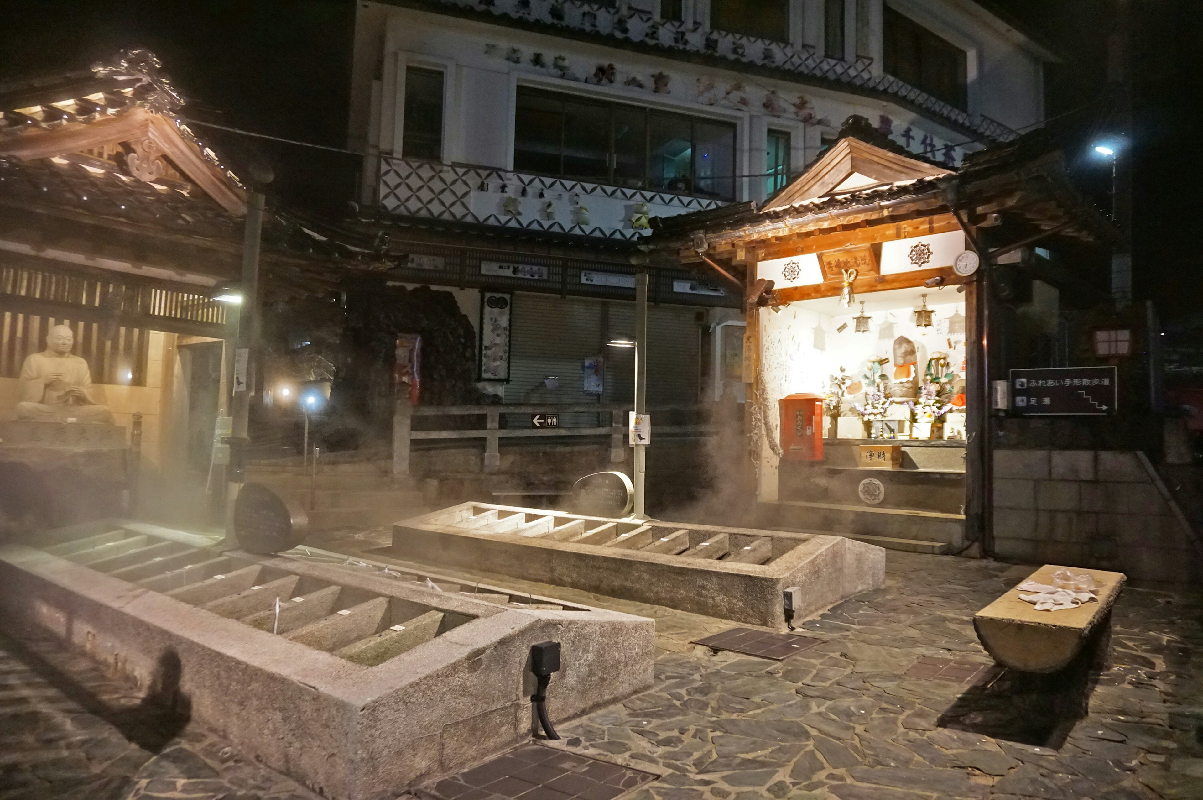 Vue nocturne d'une ville thermale avec des bâtiments traditionnels et un onsen fumant