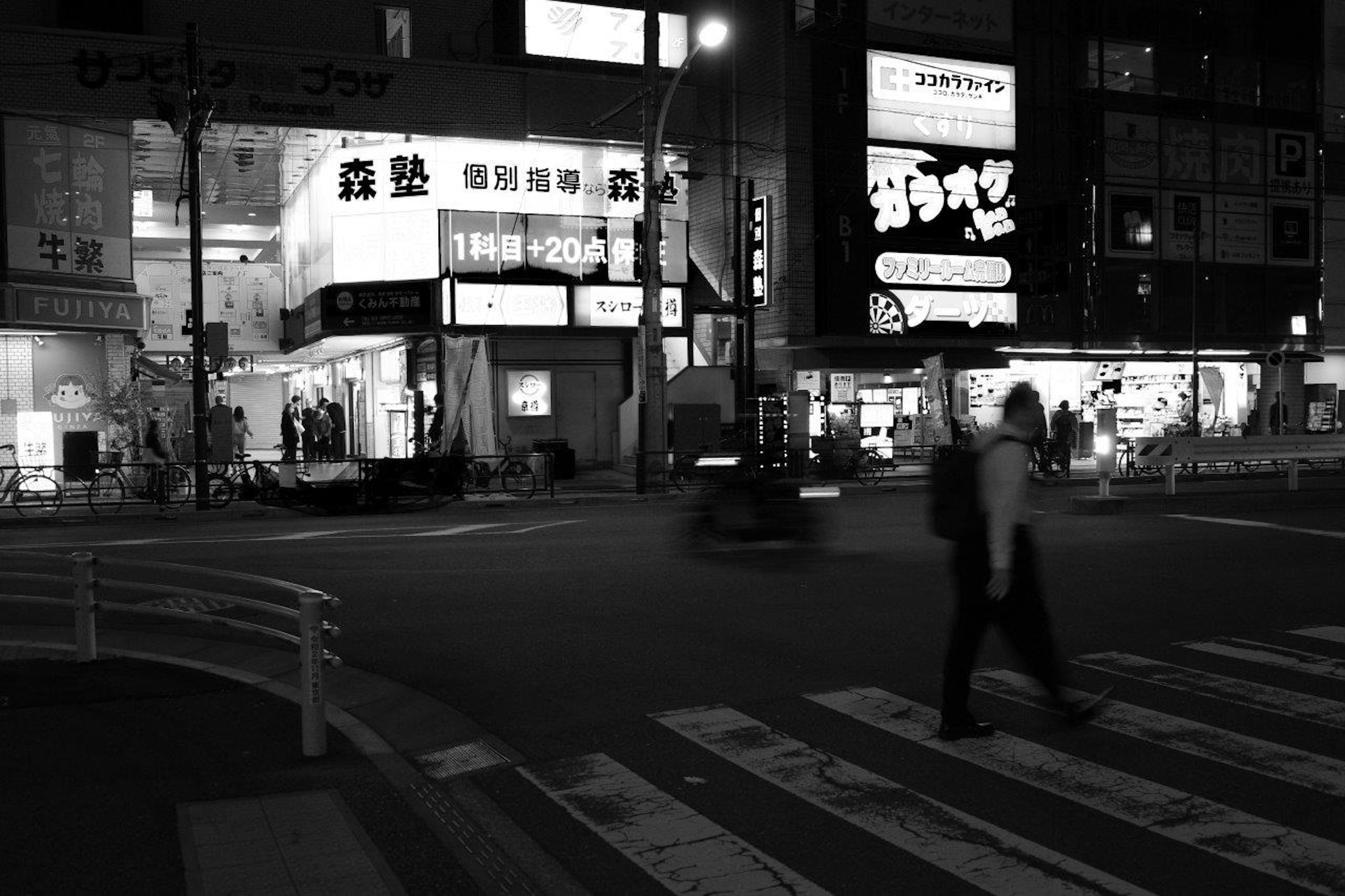 A pedestrian crossing the crosswalk at a city intersection at night