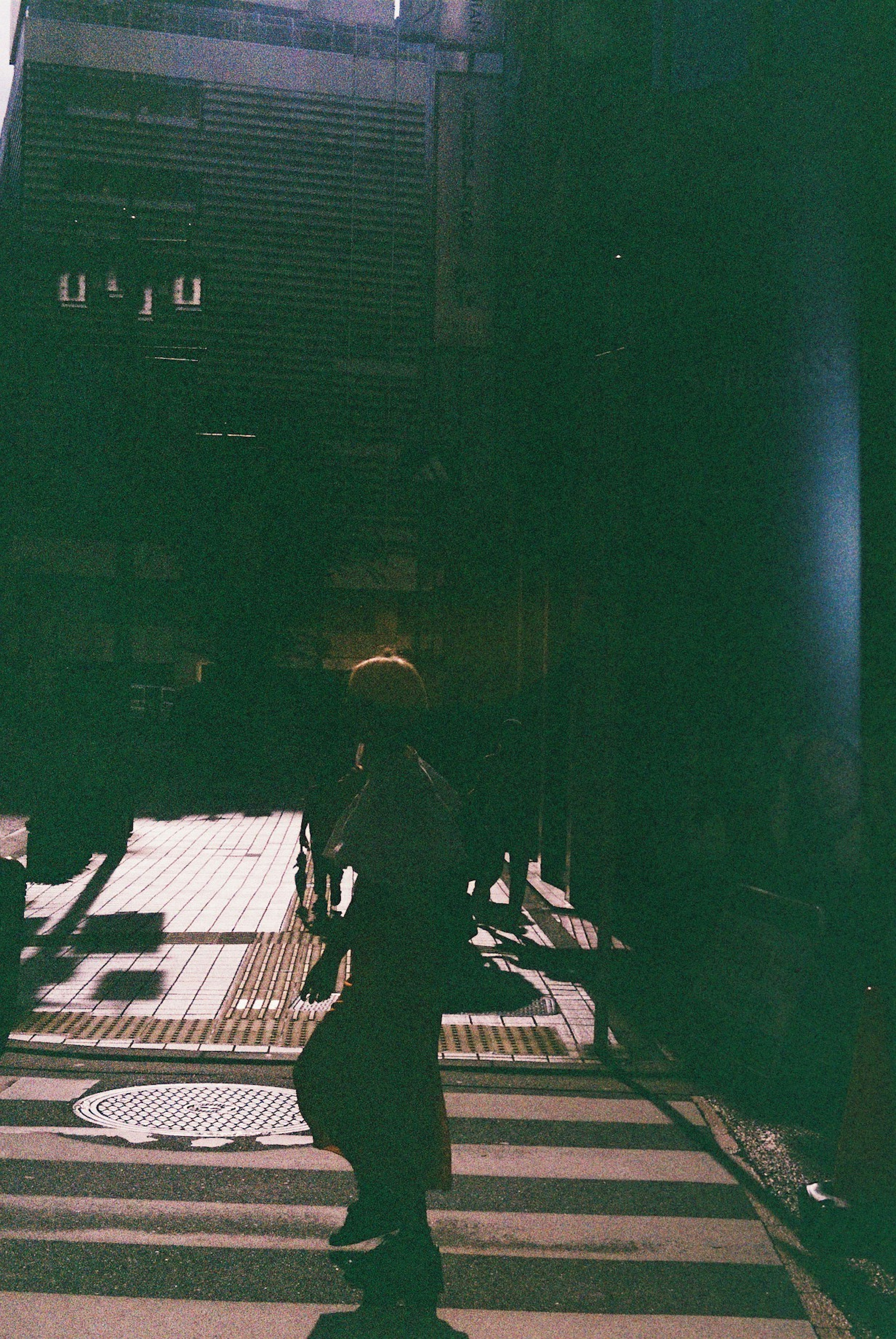 Silhouette of a person crossing a bright crosswalk against a dark background