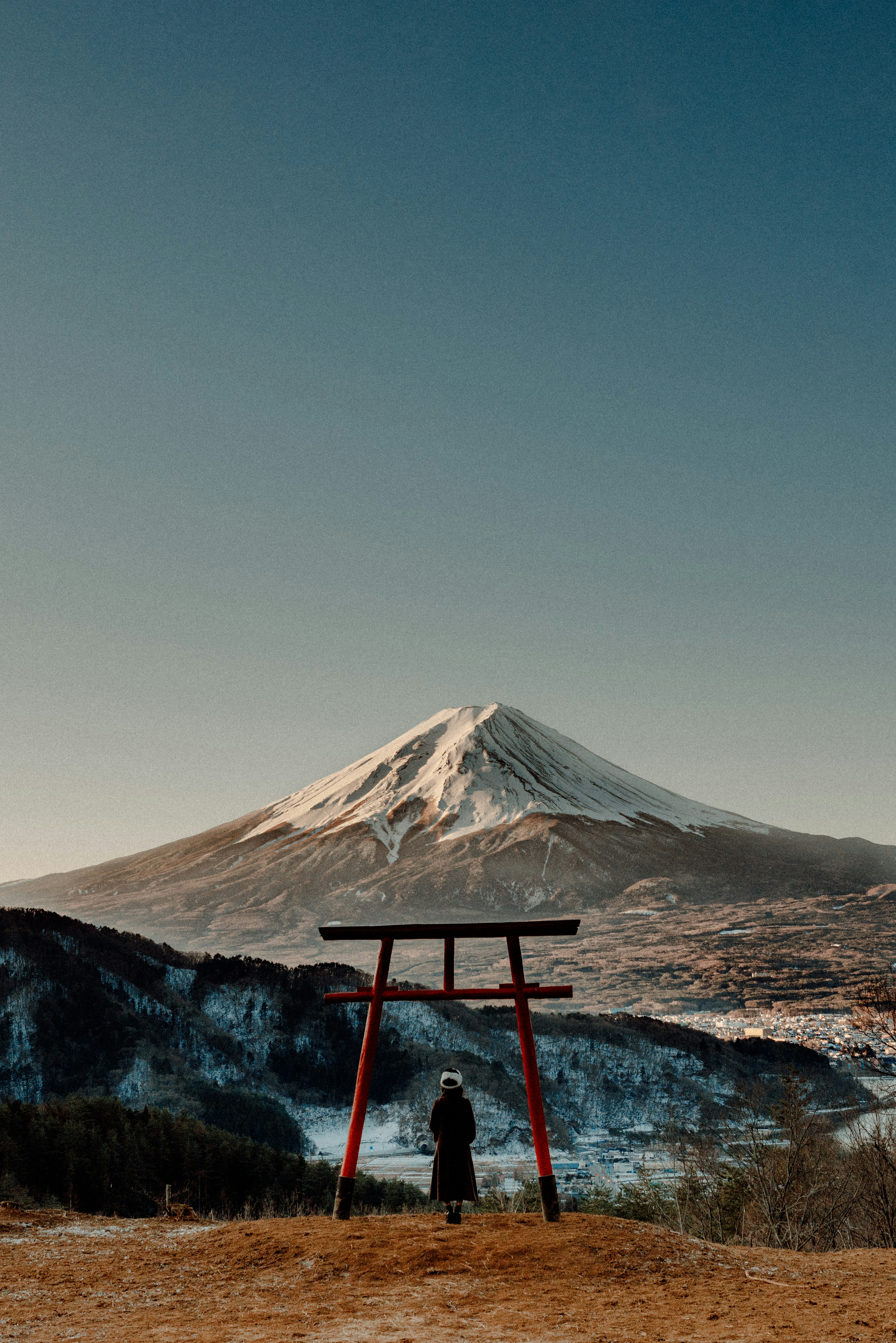 Silhouette d'une personne devant un torii rouge avec le mont Fuji en arrière-plan