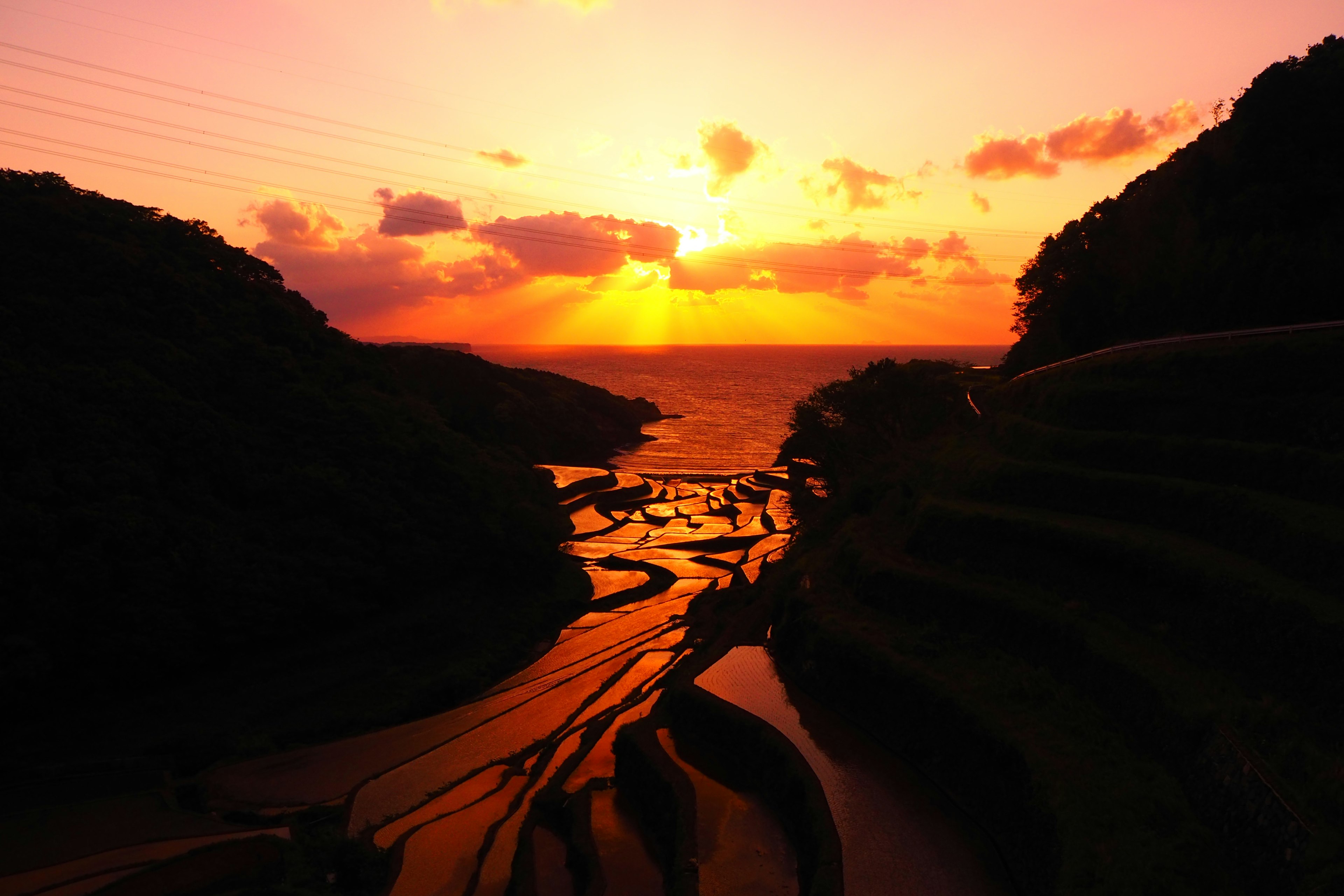 Scenic view of a sunset over a coastline with terraced fields