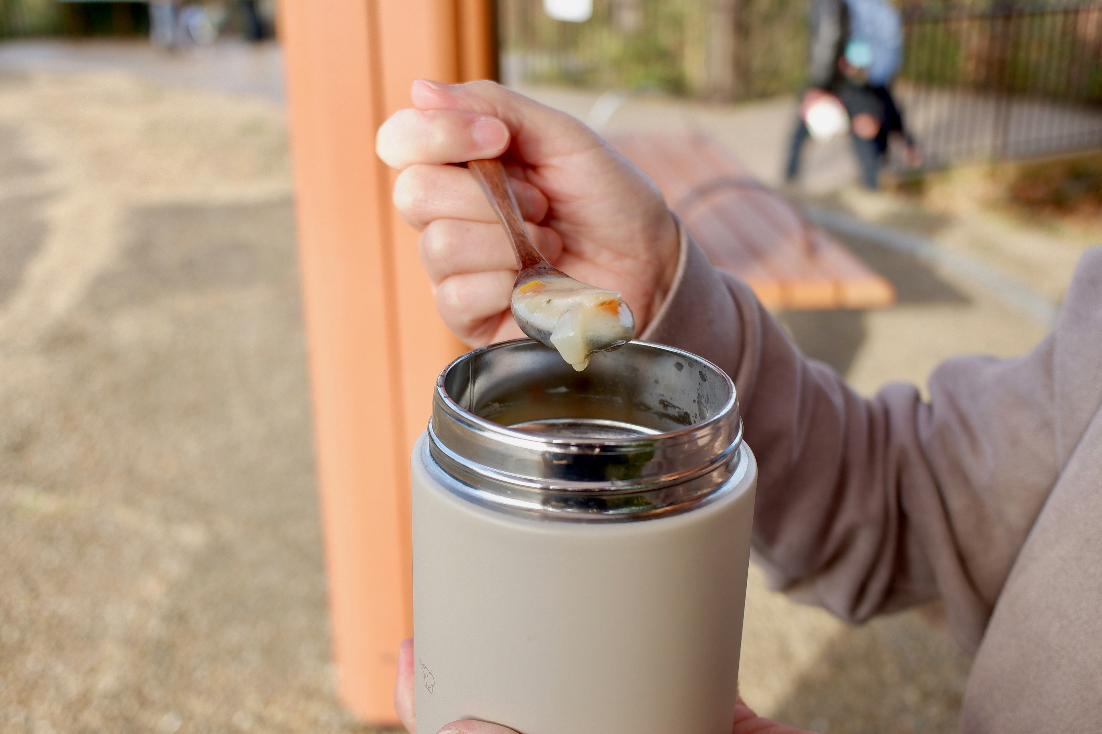 Una persona che usa un cucchiaio per prendere zuppa da un thermos