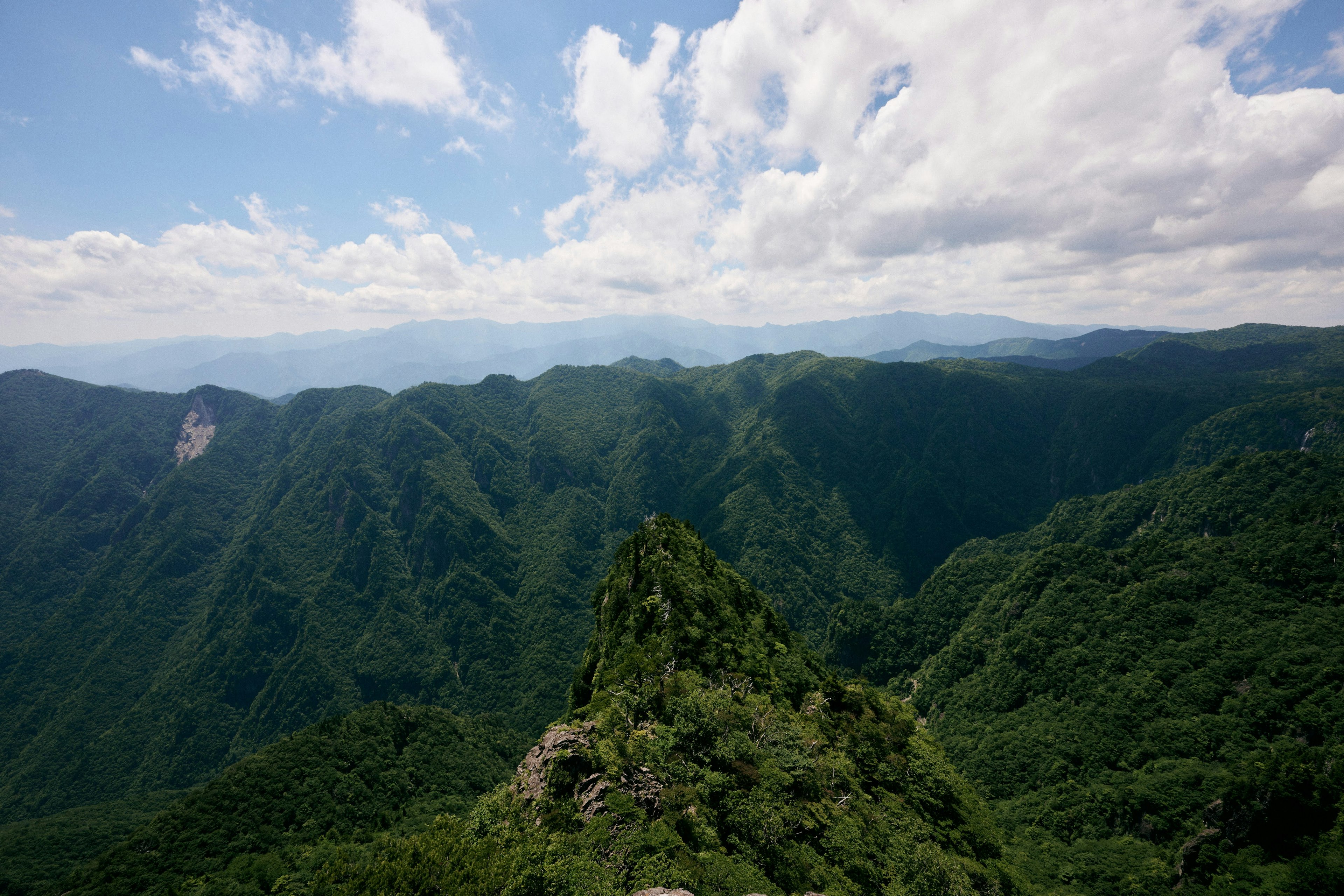 Vue panoramique sur des montagnes verdoyantes sous un ciel bleu