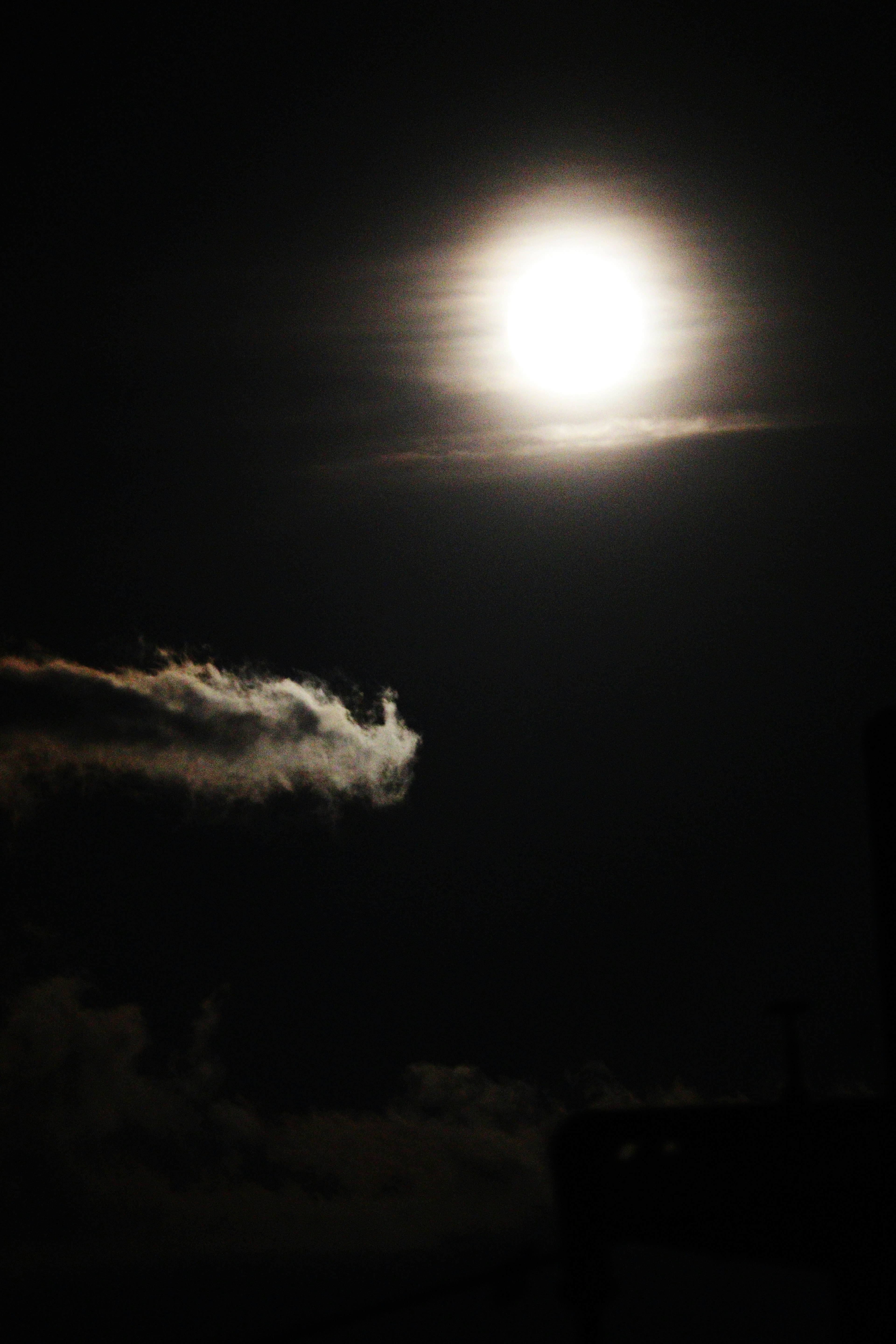 Luna llena brillante en el cielo nocturno con siluetas de nubes