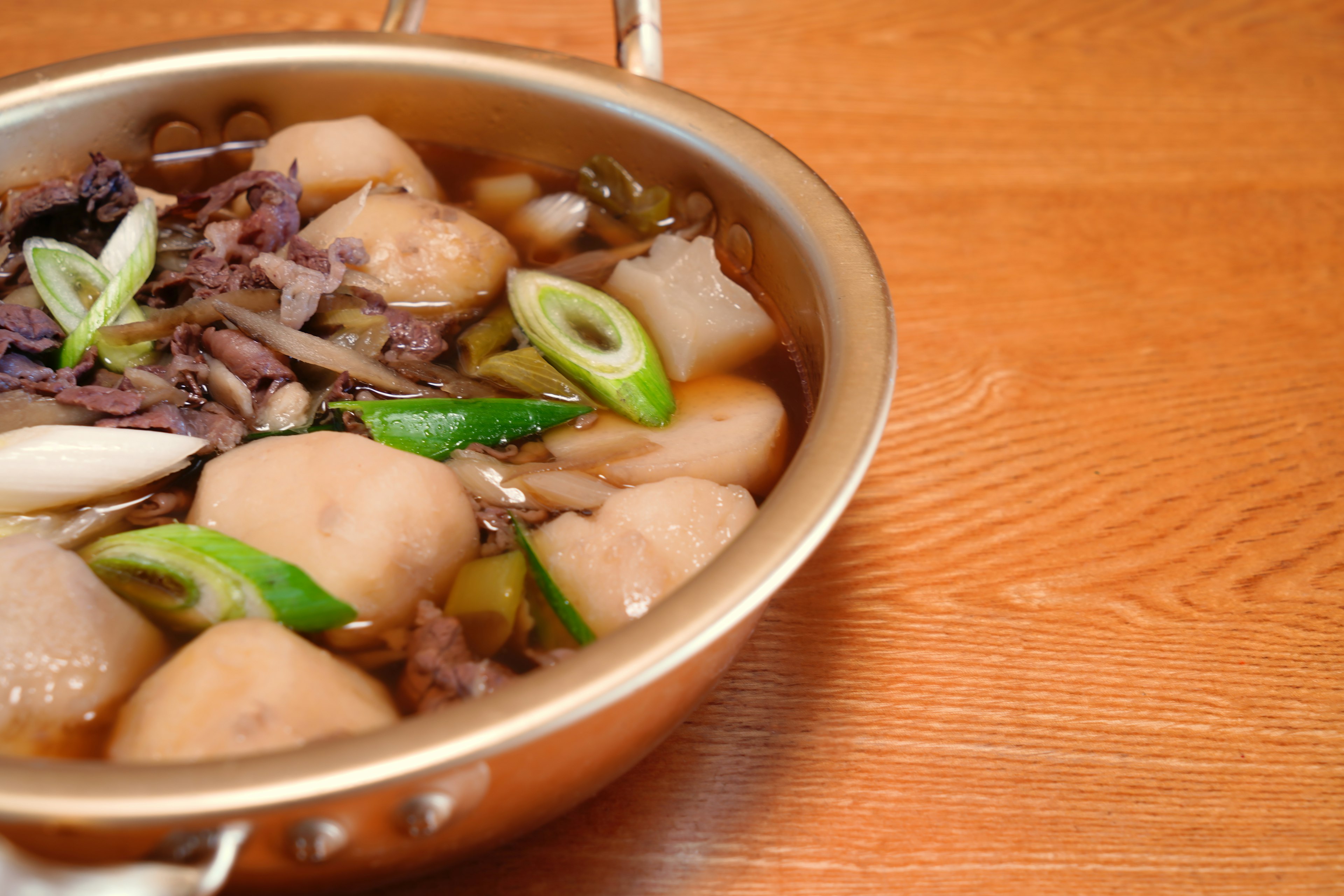 A bowl of meatballs and green onions in broth