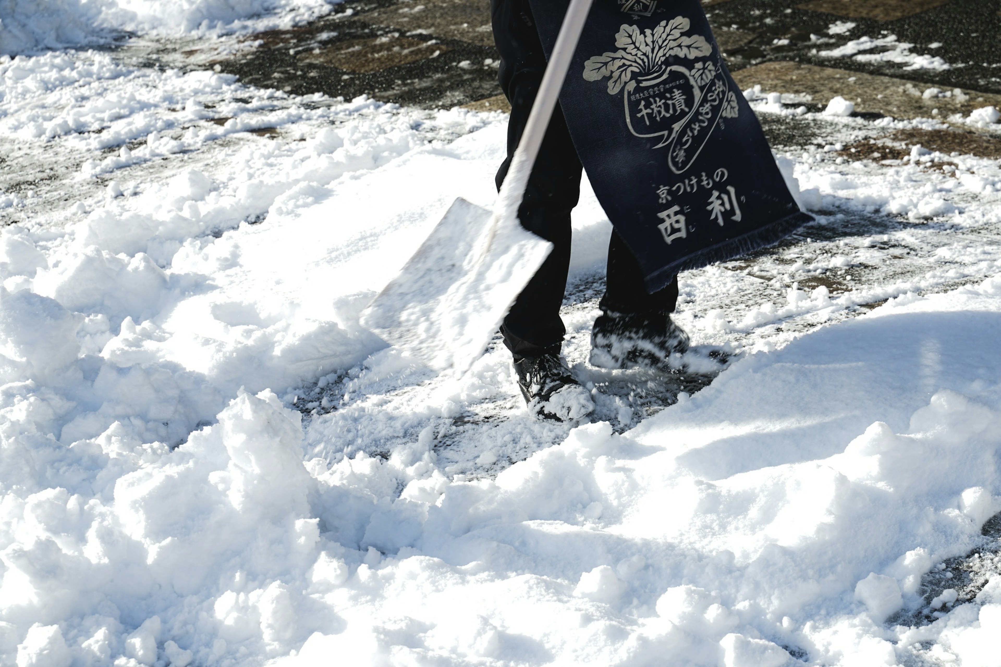 正在用鏟子鏟雪的人在雪地上