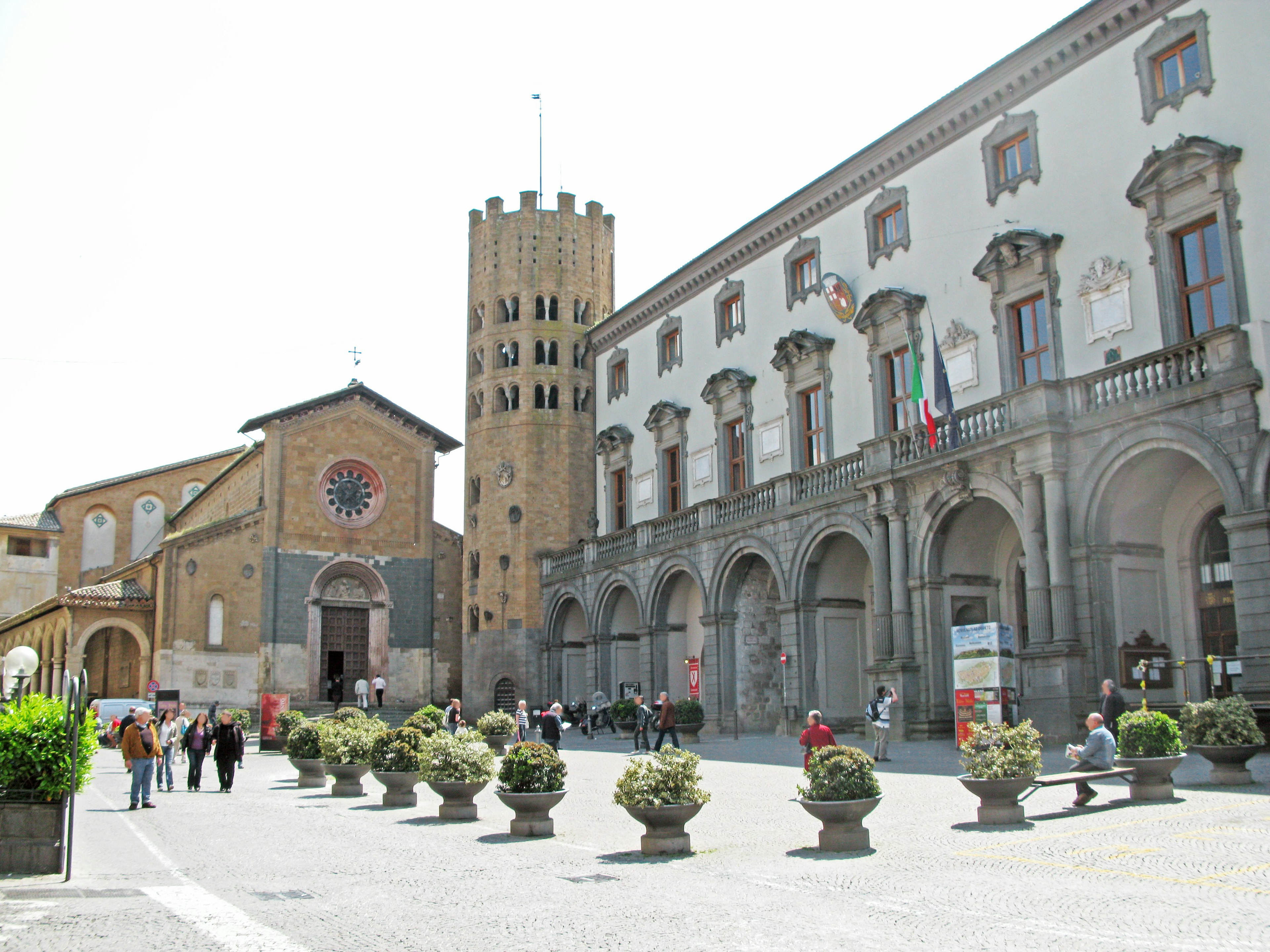 Historic buildings and a tower in a square with people walking