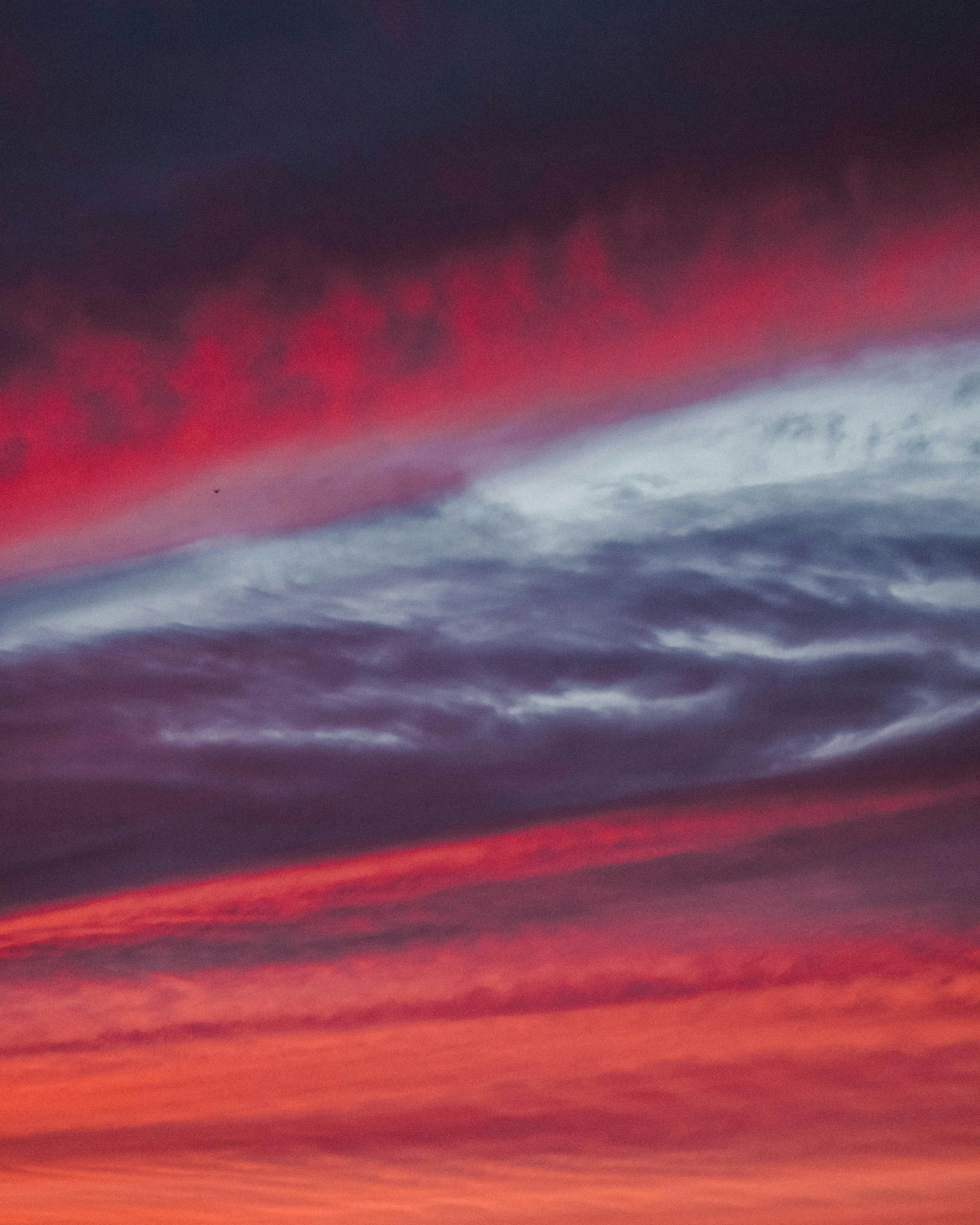 赤と紫の美しい夕焼け空に白い雲が浮かぶ