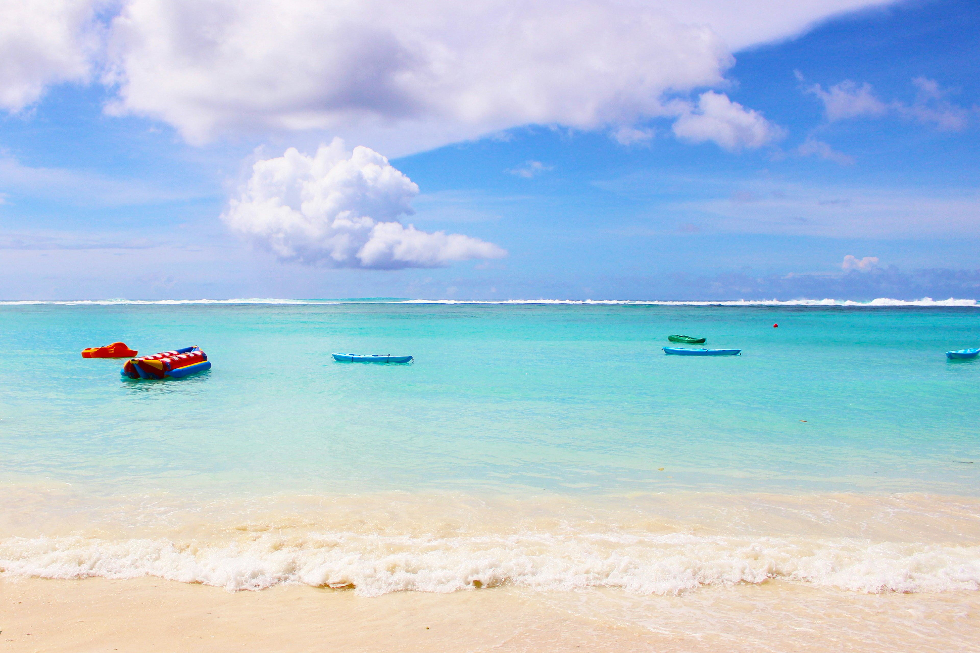 Colorful boats floating on a blue ocean with a sandy beach