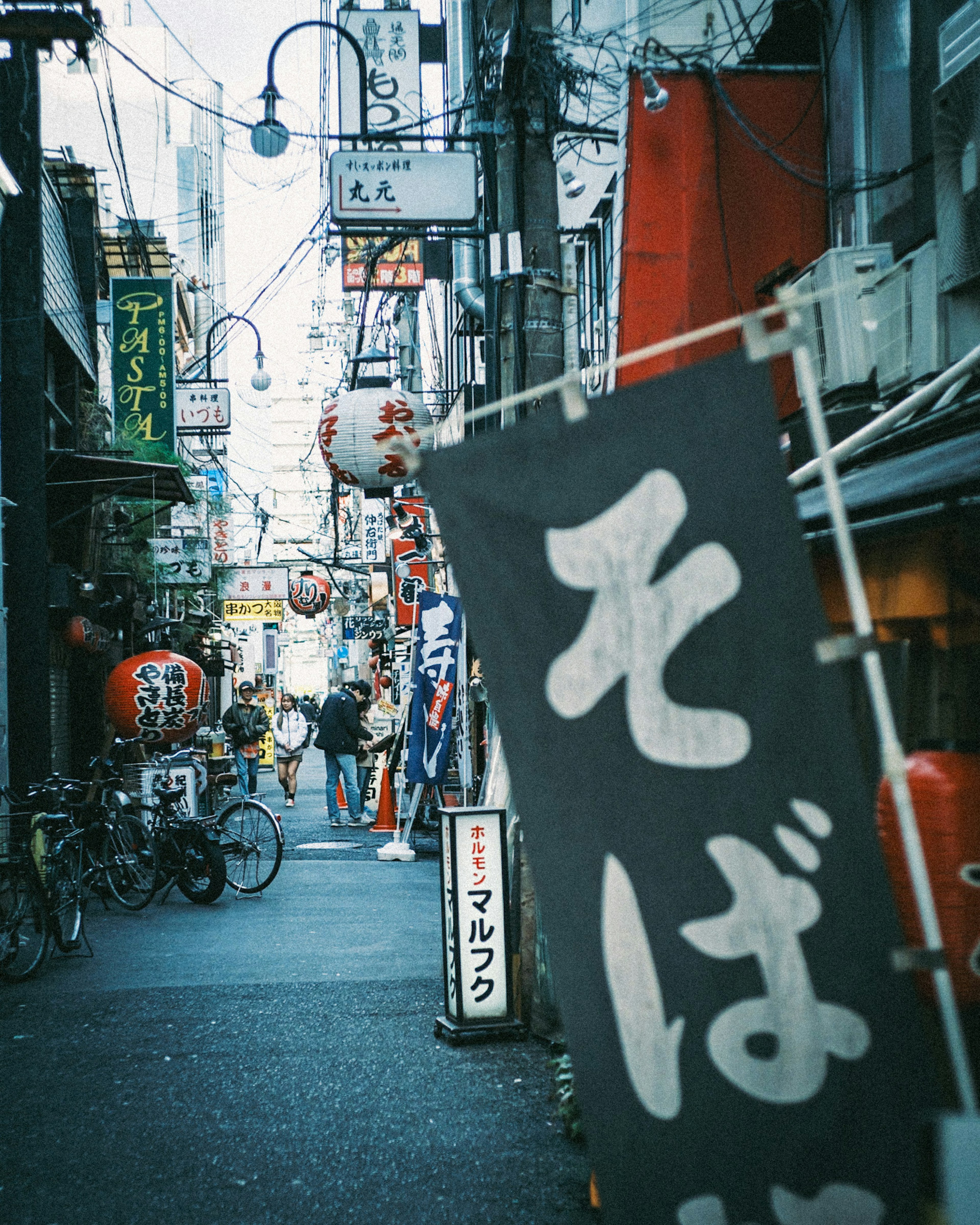 A lively street with a soba shop sign and surrounding eateries