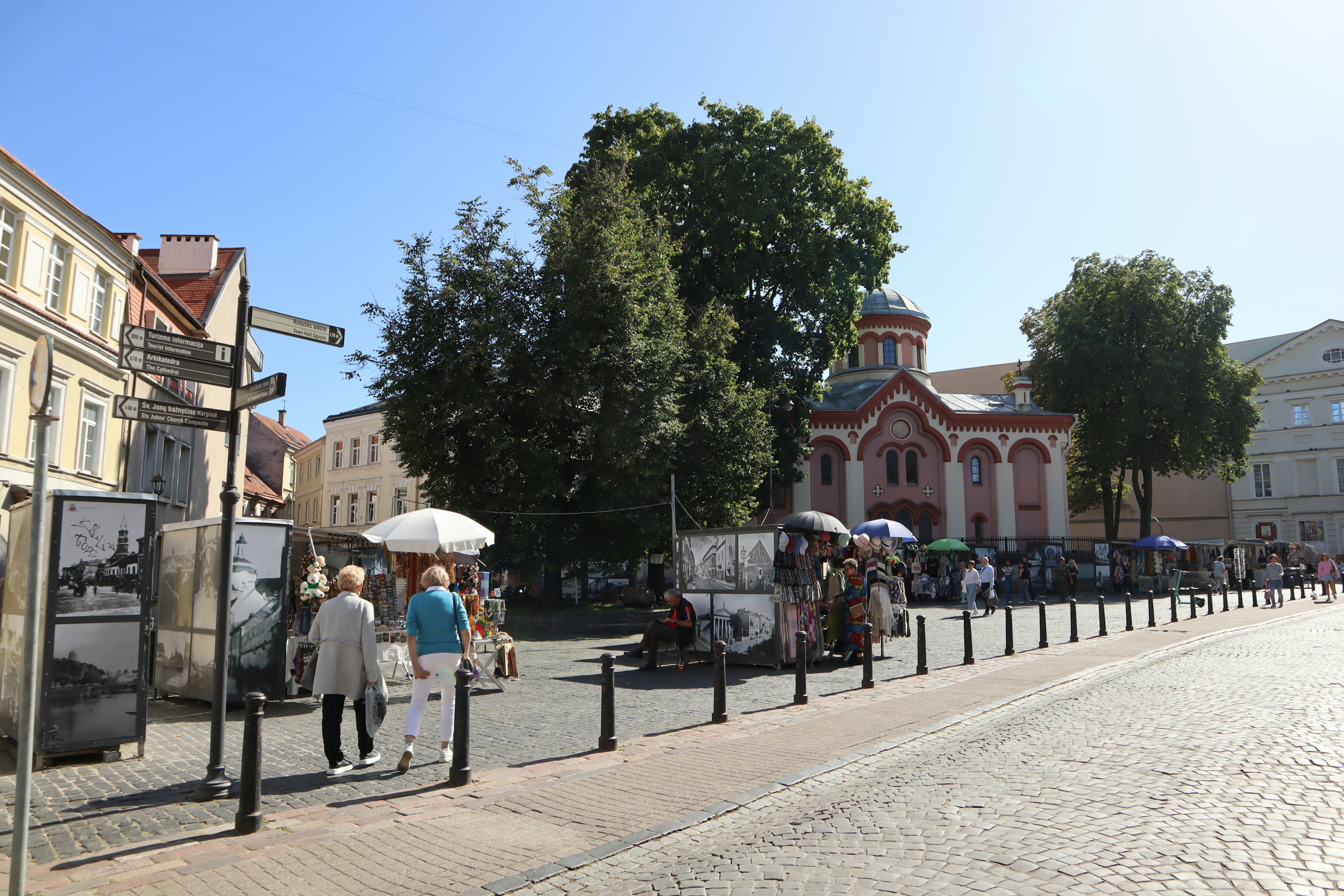 Lively street scene with trees and buildings people walking with umbrellas