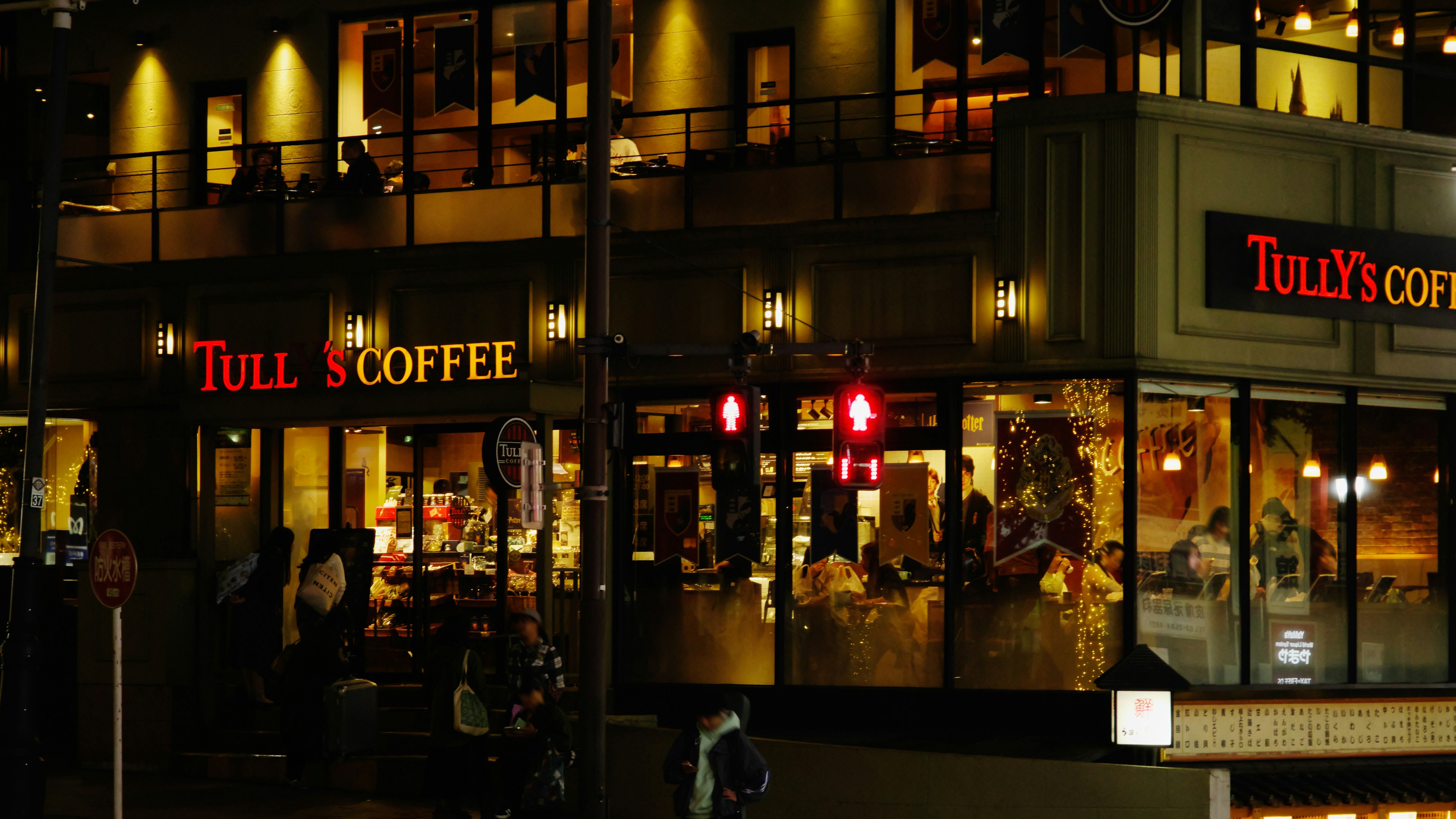 Vista exterior de Tully's Coffee de noche con luces brillantes y decoraciones en las ventanas