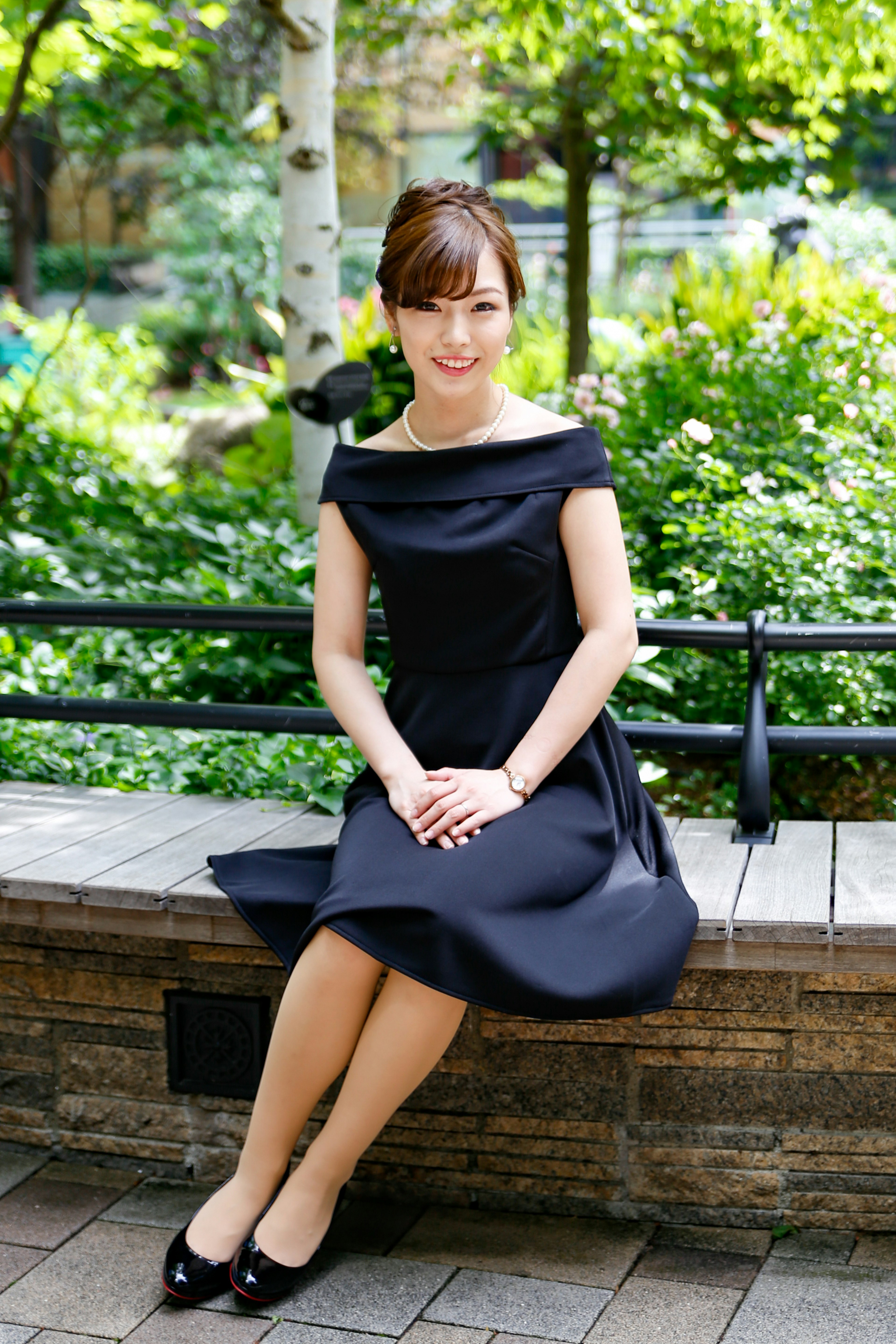 A woman wearing a black dress sitting on a park bench