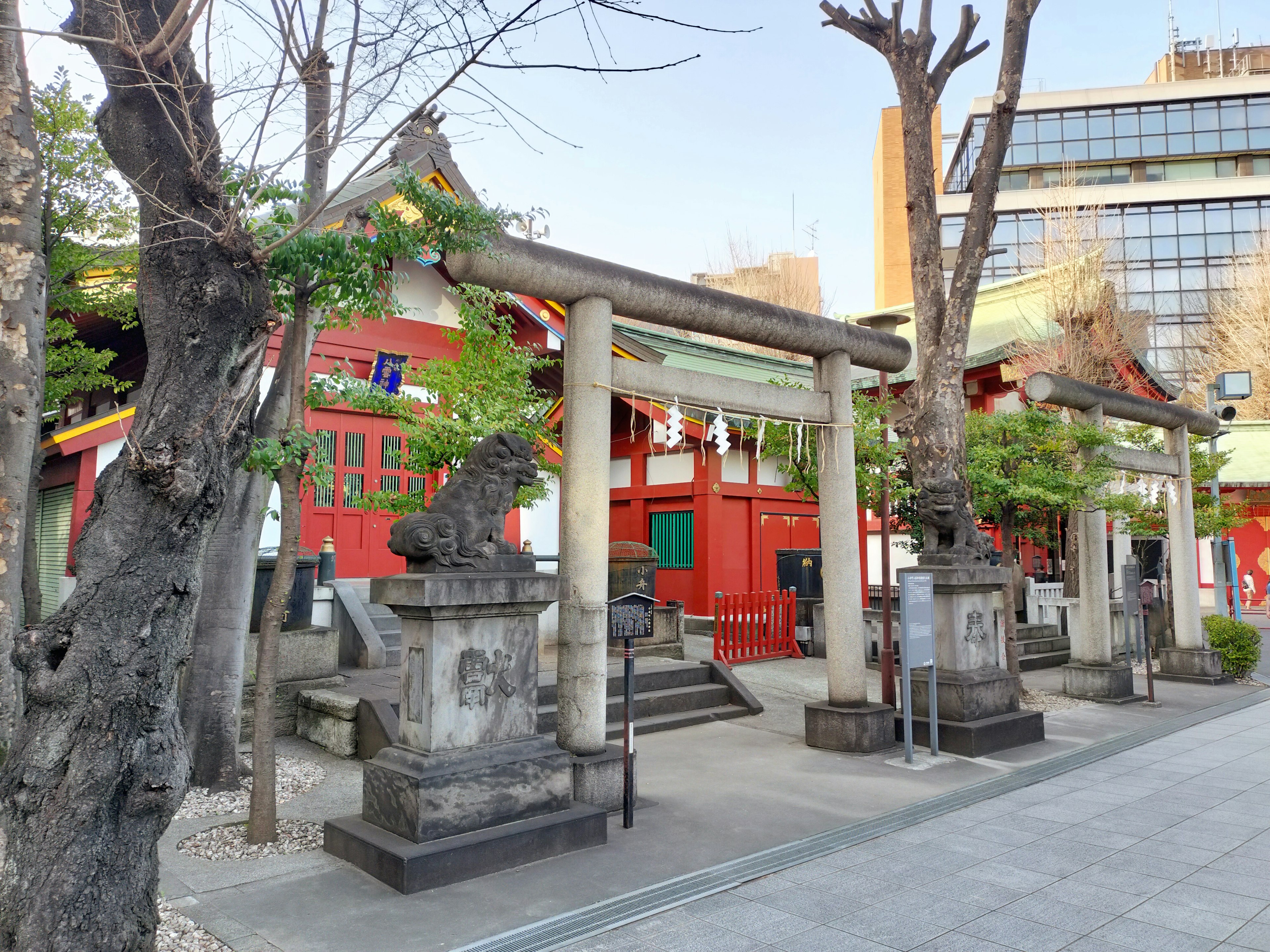 Vista escénica de un santuario con un edificio rojo y leones guardianes de piedra