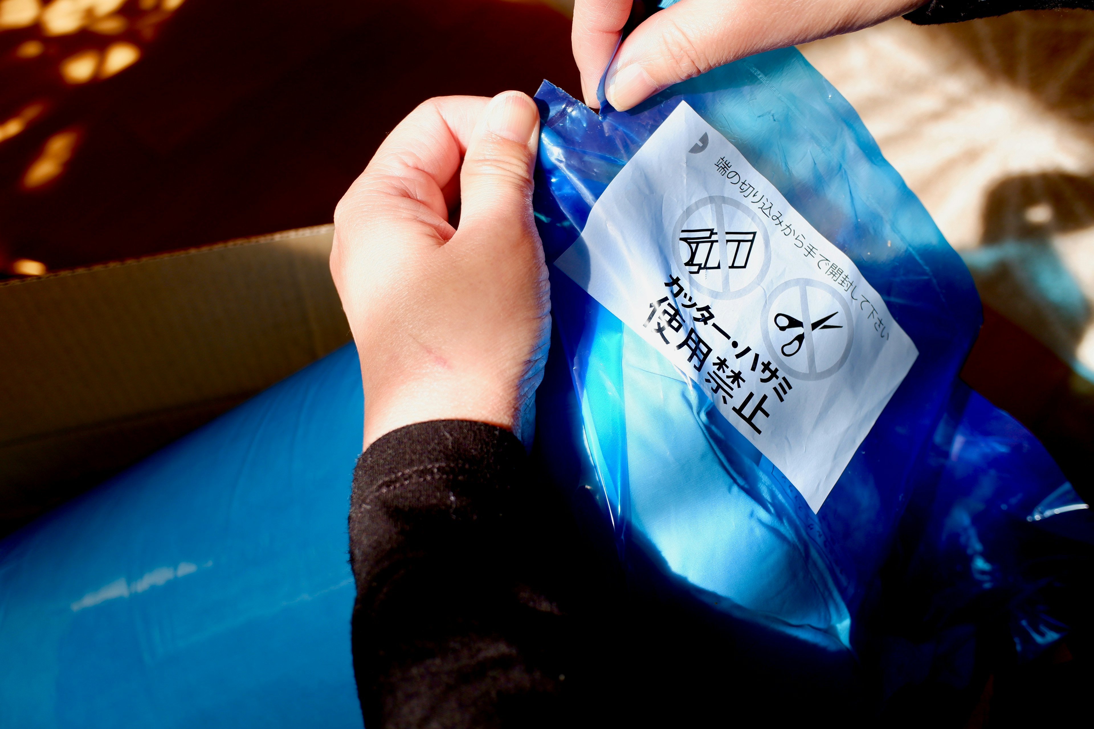 Hands opening a blue package with a visible label