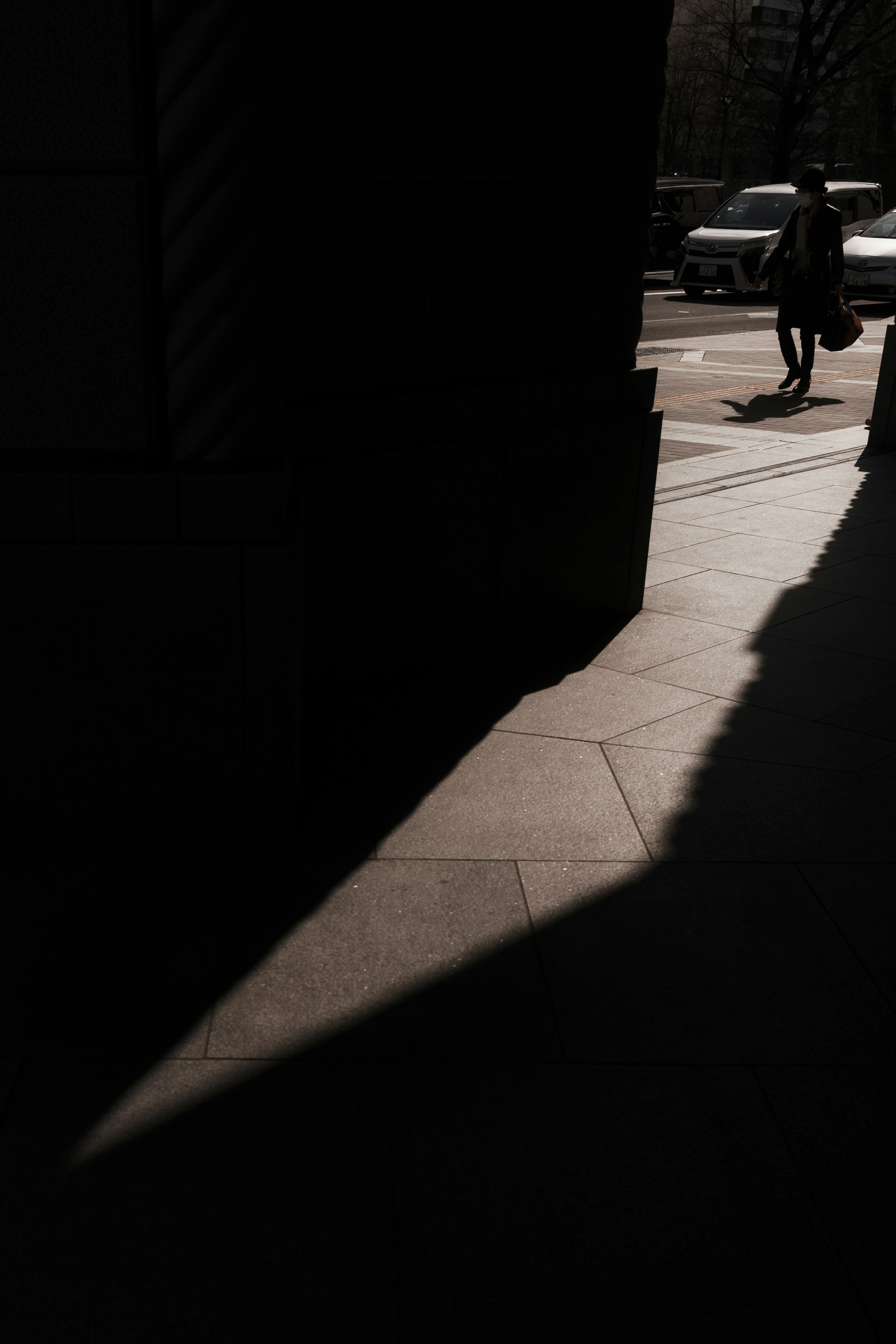 Silhouette di un angolo di strada con ombre e una persona che cammina