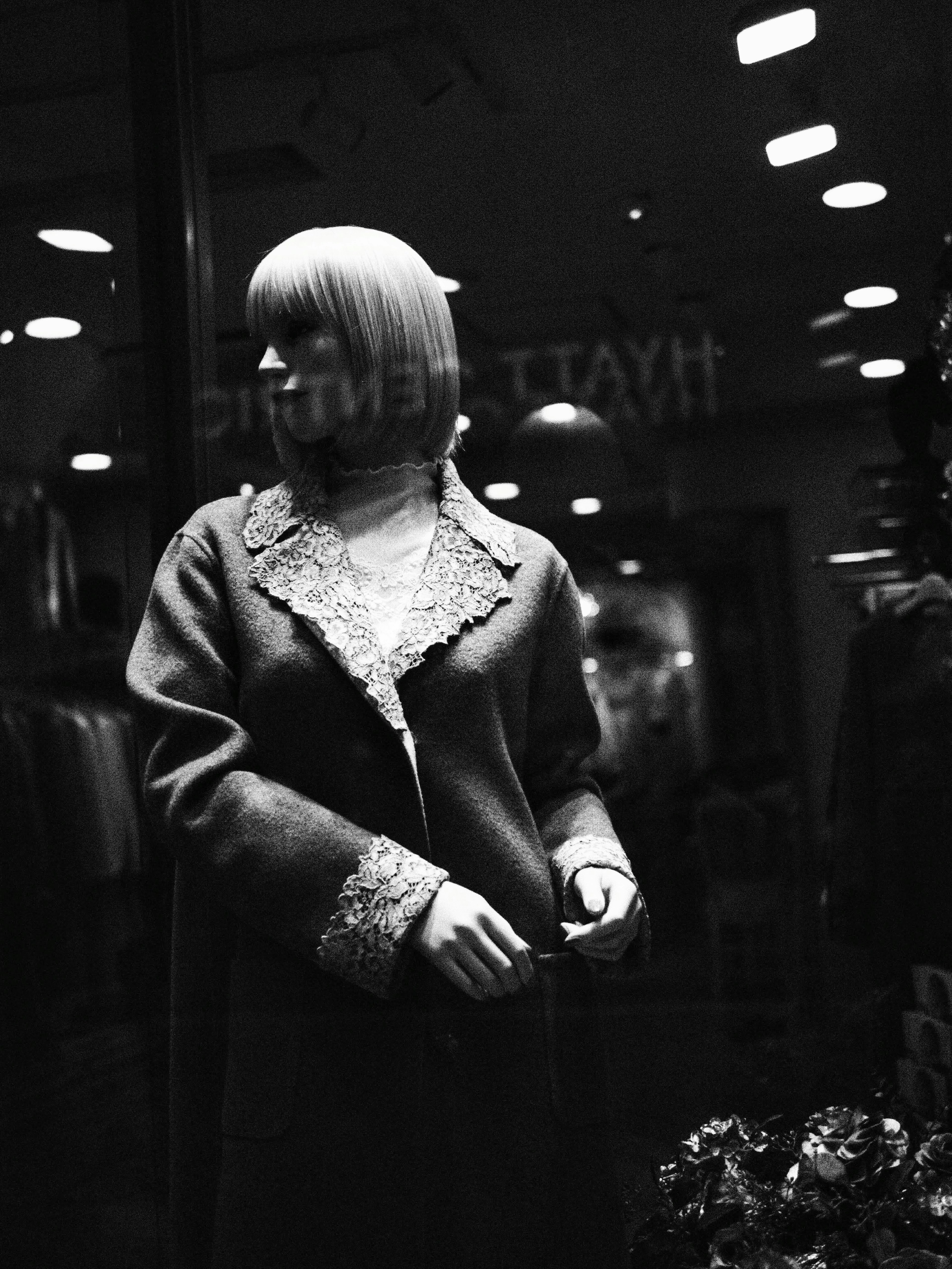 Weiblicher Mannequin in Vintage-Mode in einem schwarz-weißen Schaufenster ausgestellt