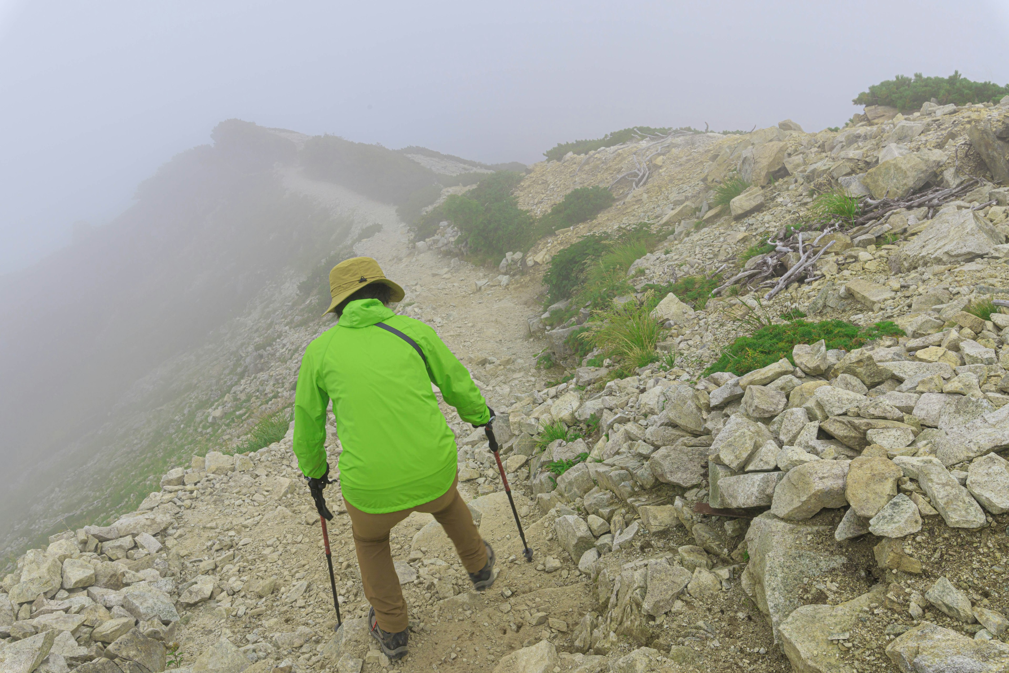 Randonneur marchant dans le brouillard portant une veste verte