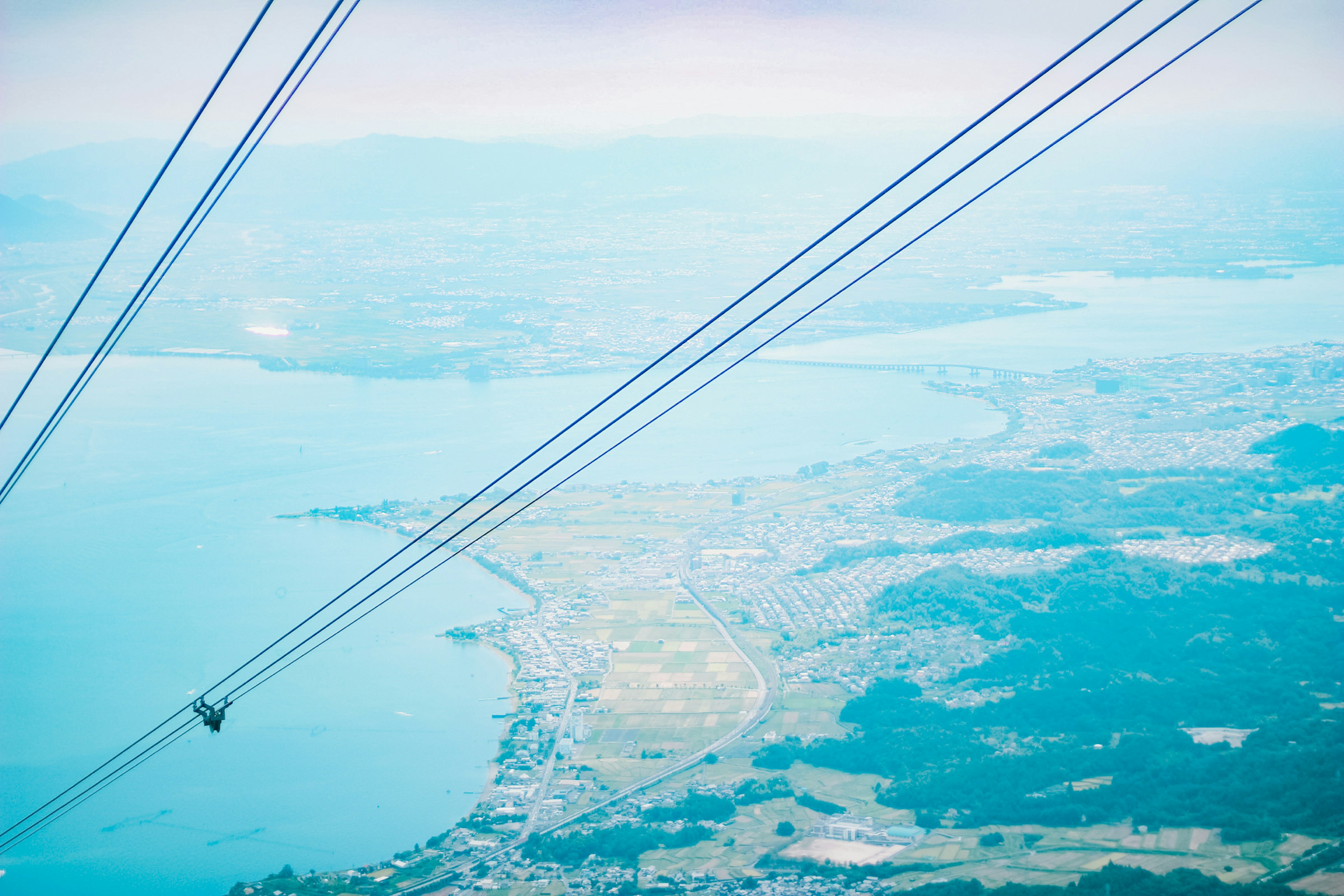 Aerial view of a scenic landscape with cable car wires in the foreground