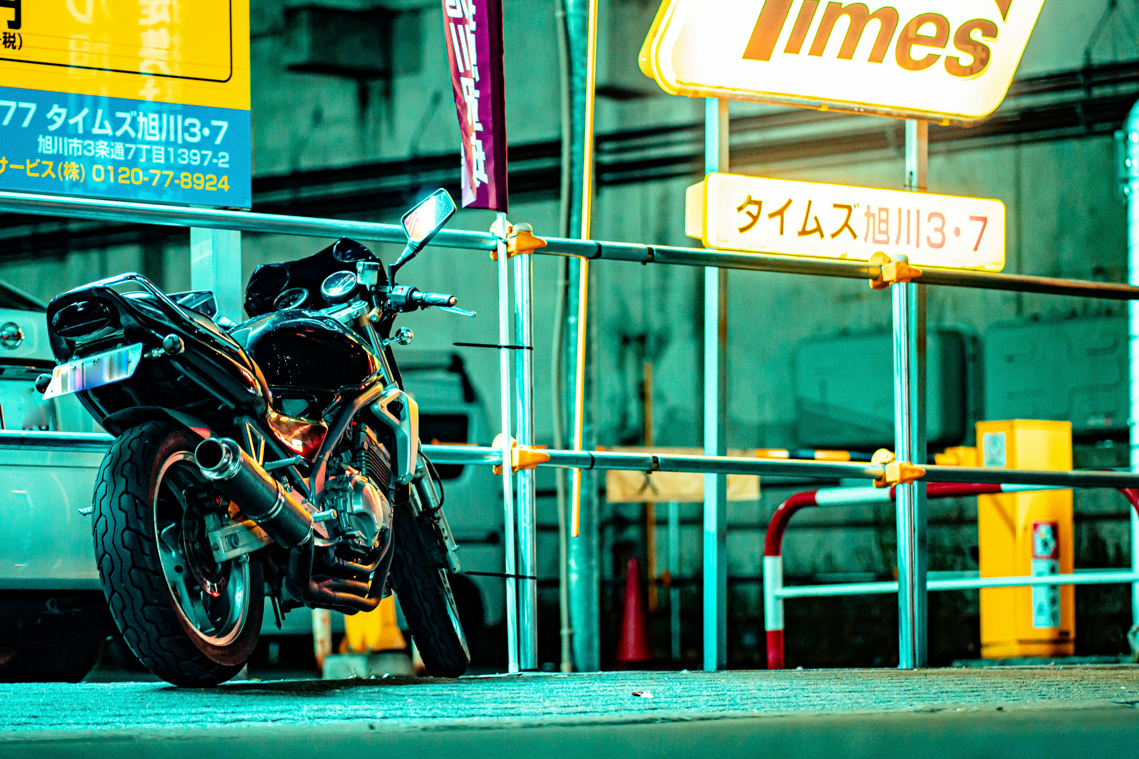 Una motocicleta estacionada en un área urbana iluminada con un letrero de estacionamiento