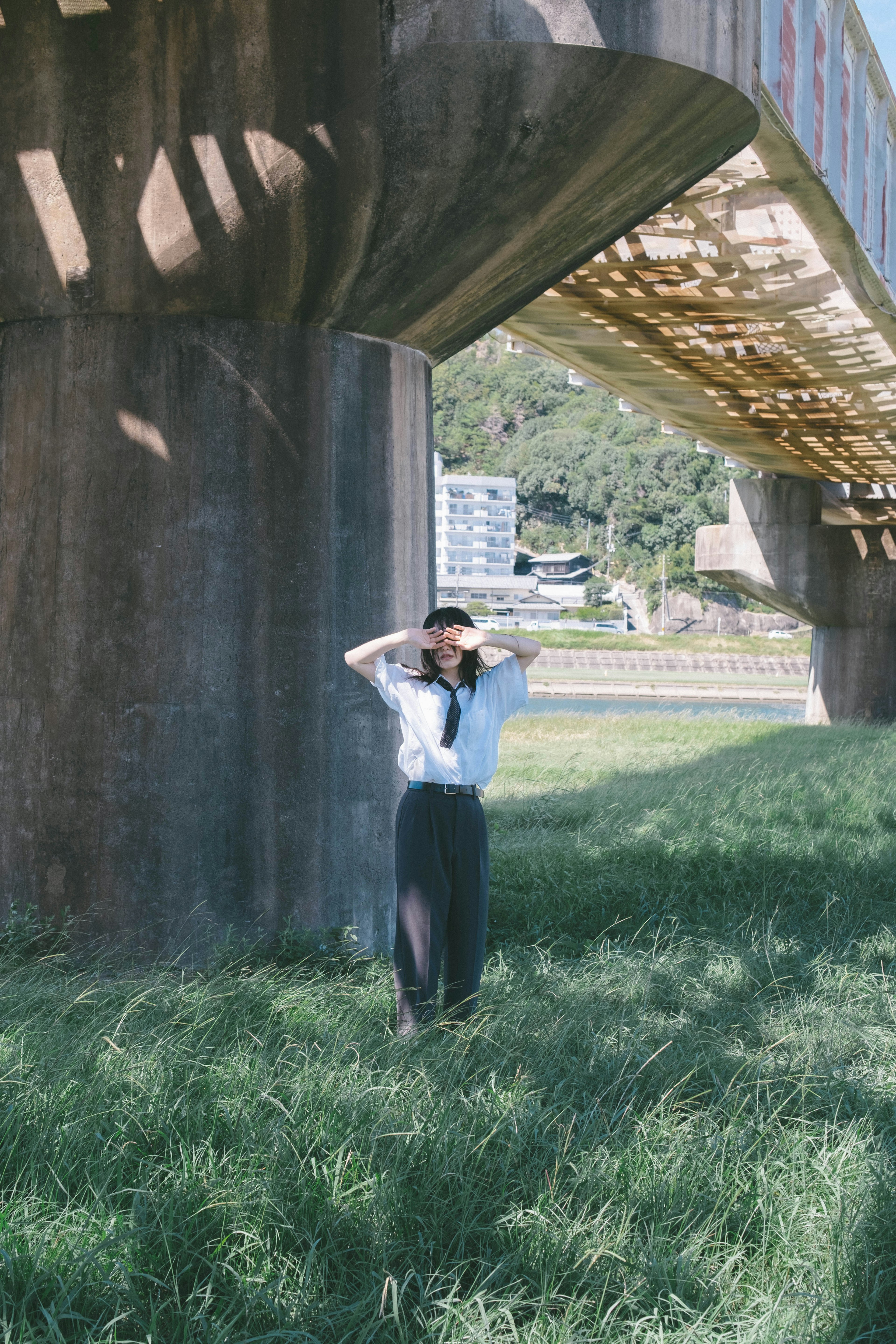 Mujer posando debajo de un puente de pie sobre la hierba