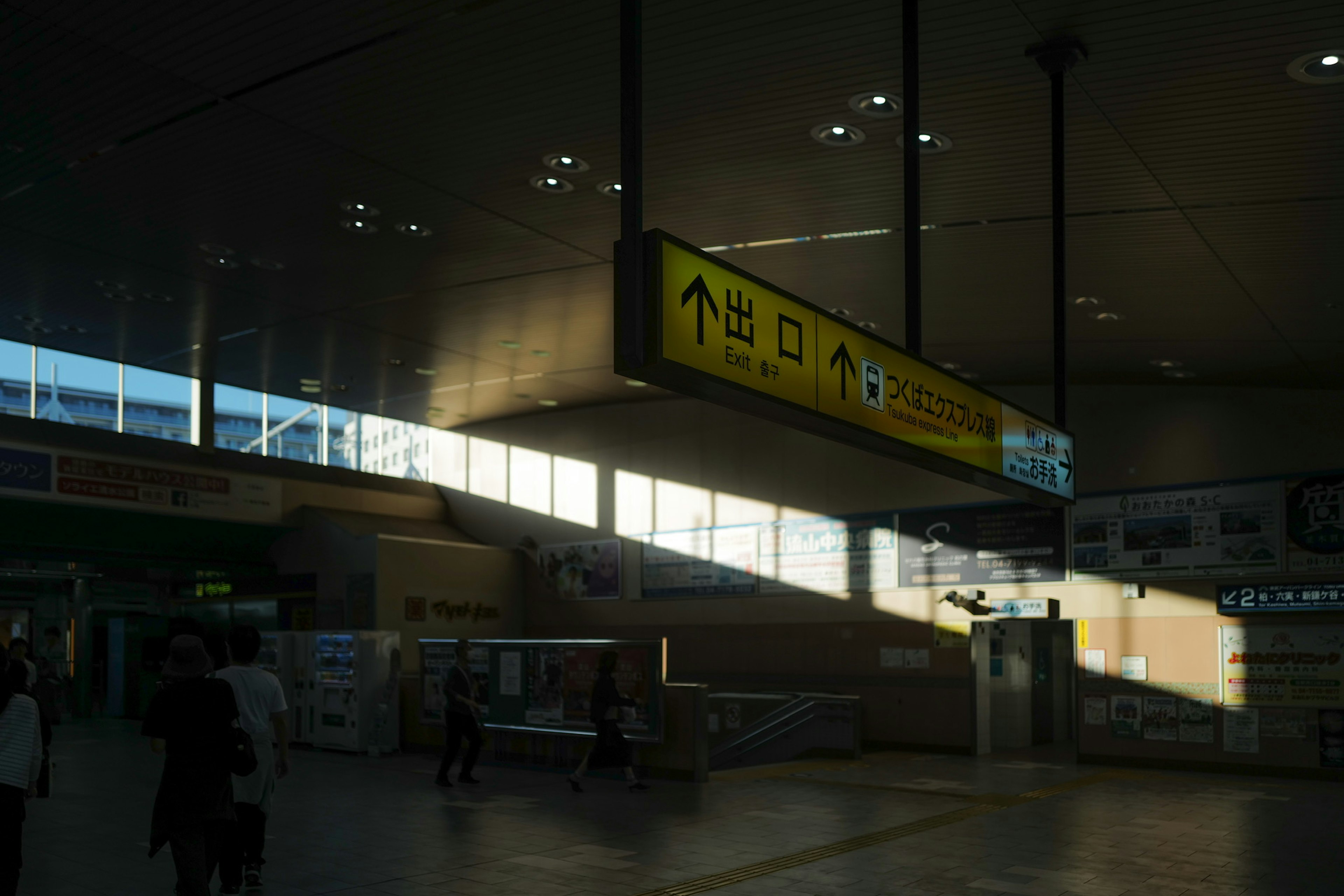 Interno di una stazione ferroviaria con segnali direzionali luminosi e persone