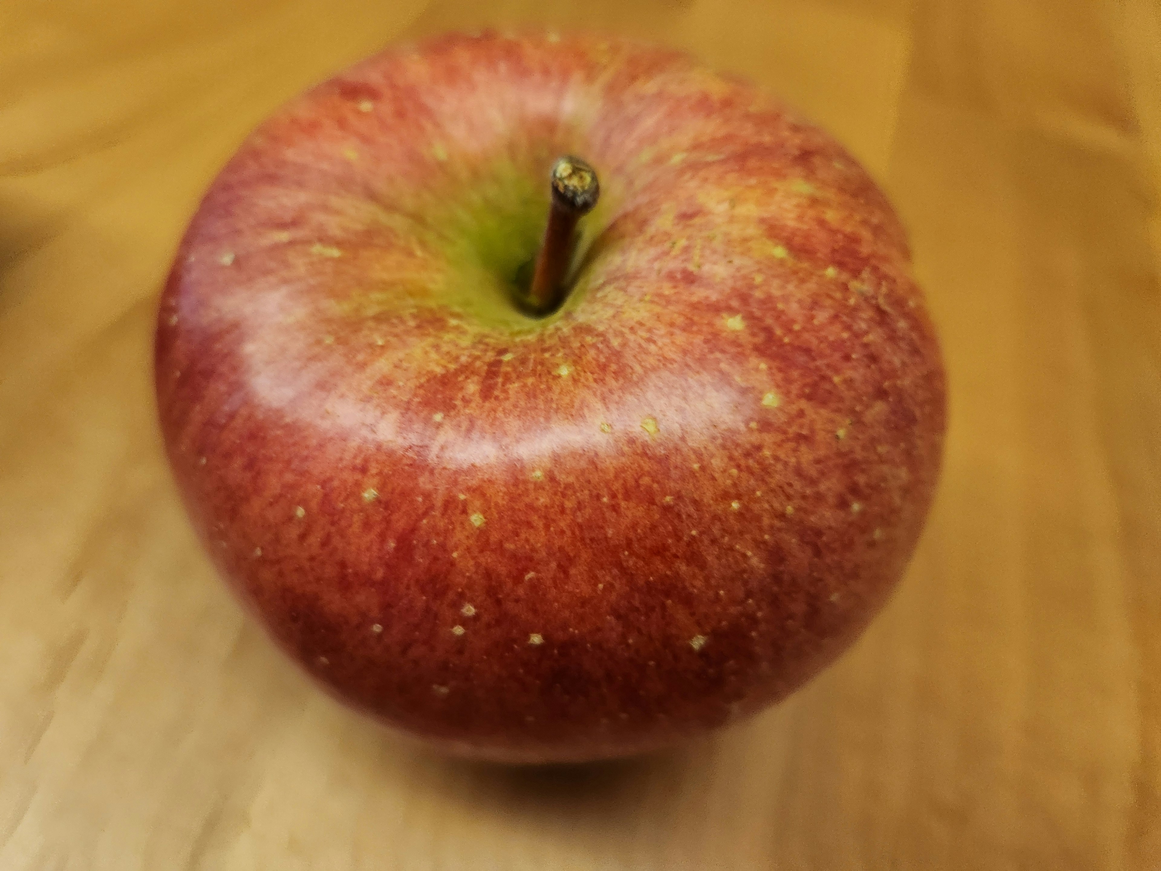 Une pomme rouge avec une tige verte sur une table en bois