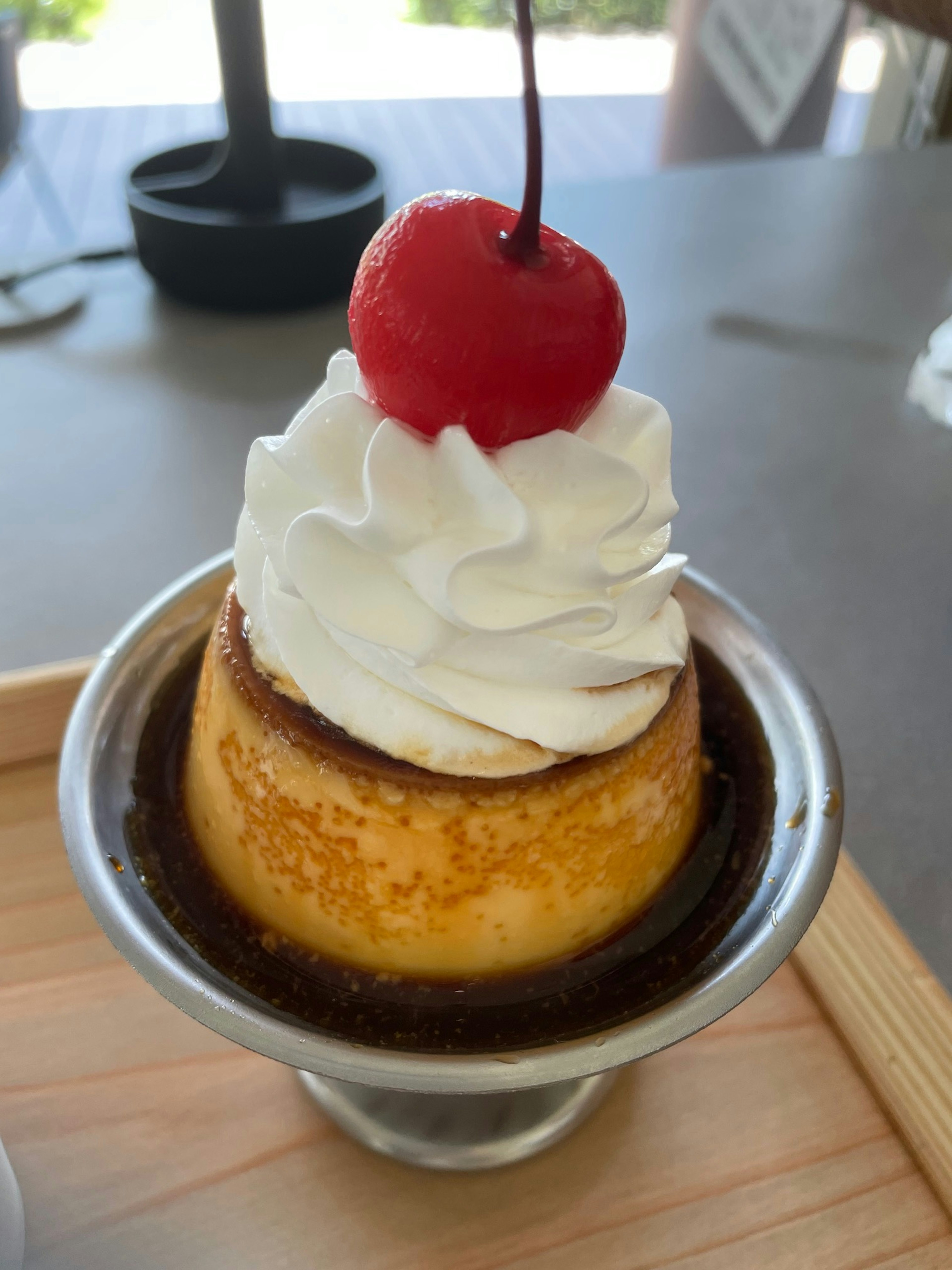 Flan de postre cubierto con crema batida y una cereza