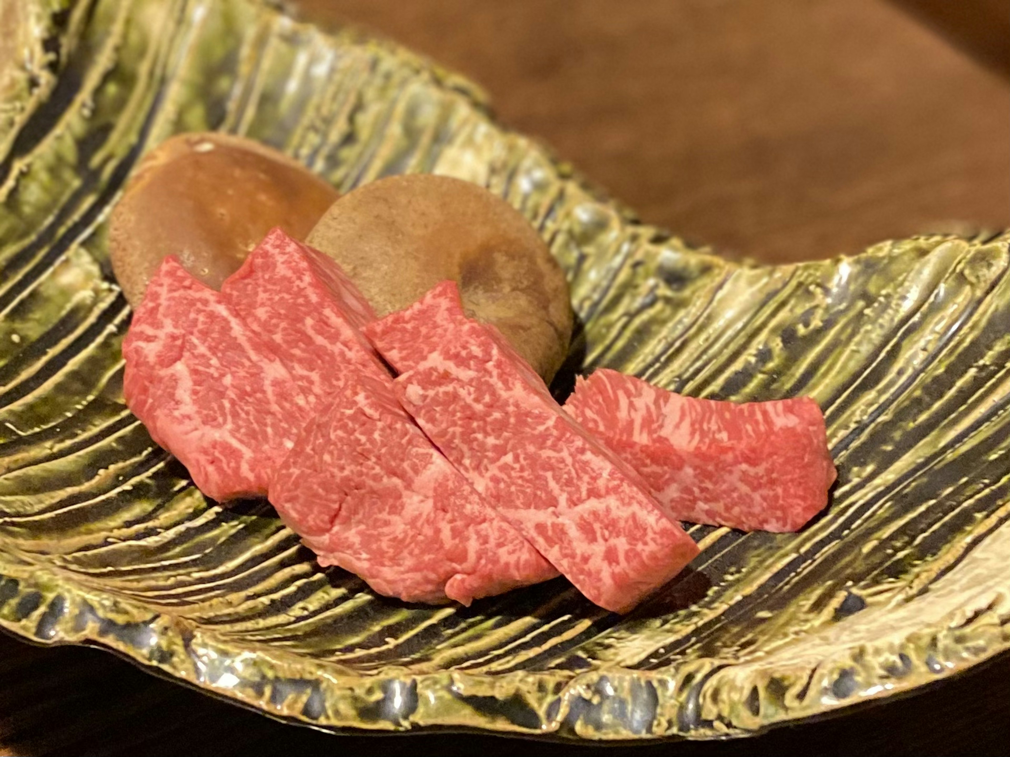 Beautiful green plate with slices of wagyu beef and sweet potato