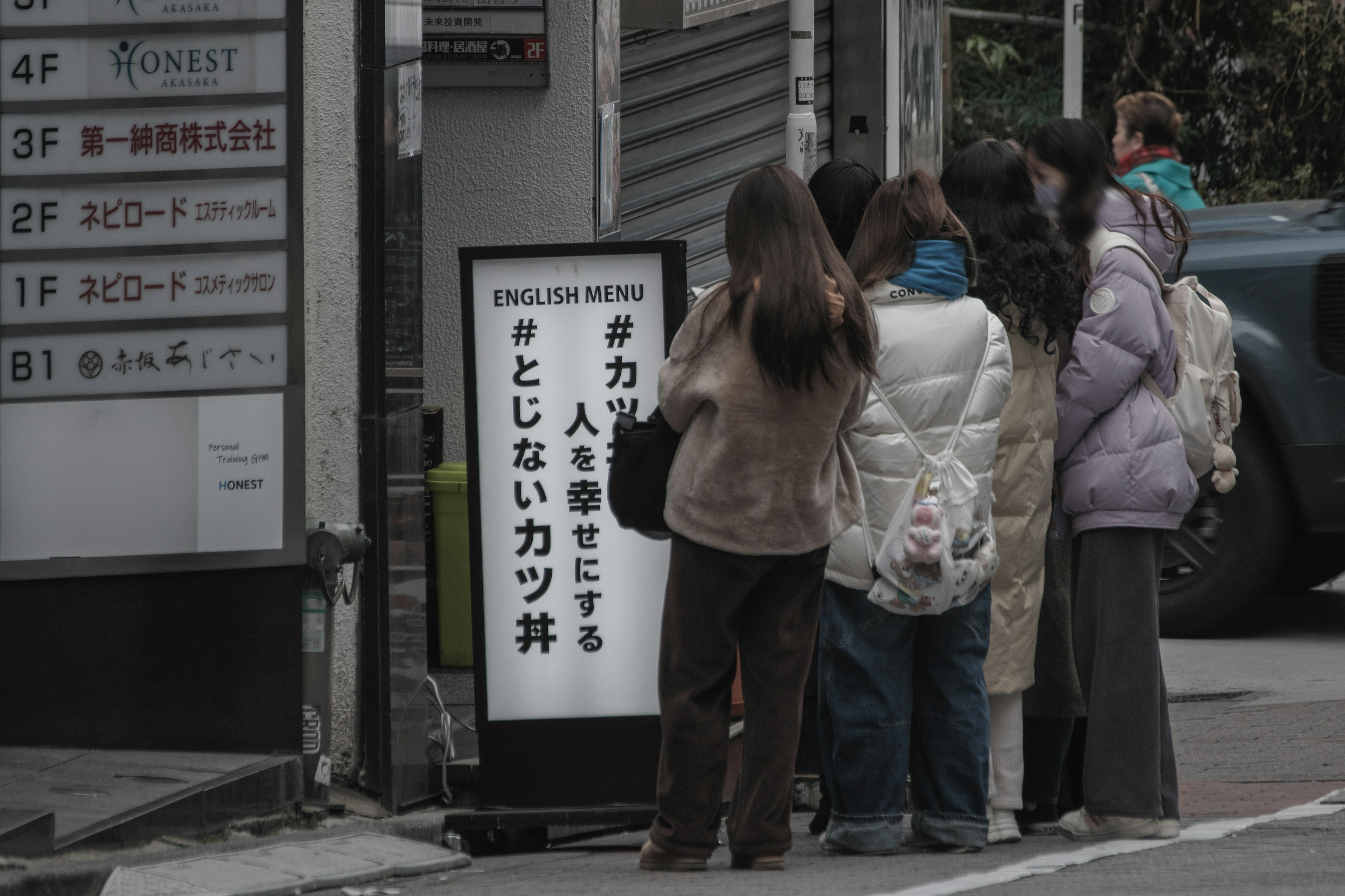 人々が並んでいる飲食店の看板が見える