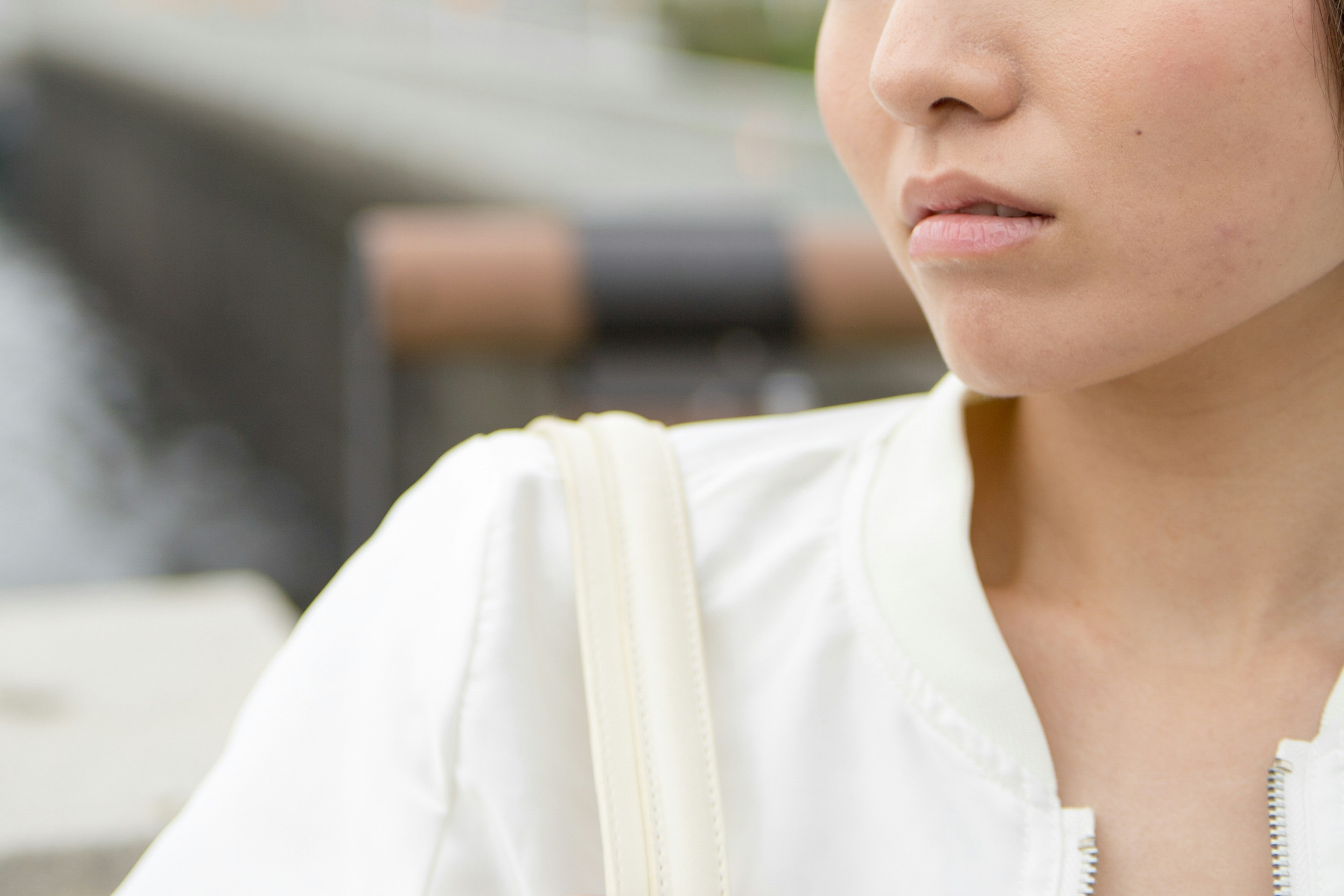 A close-up of a woman wearing a white jacket with her shoulder and part of her face visible