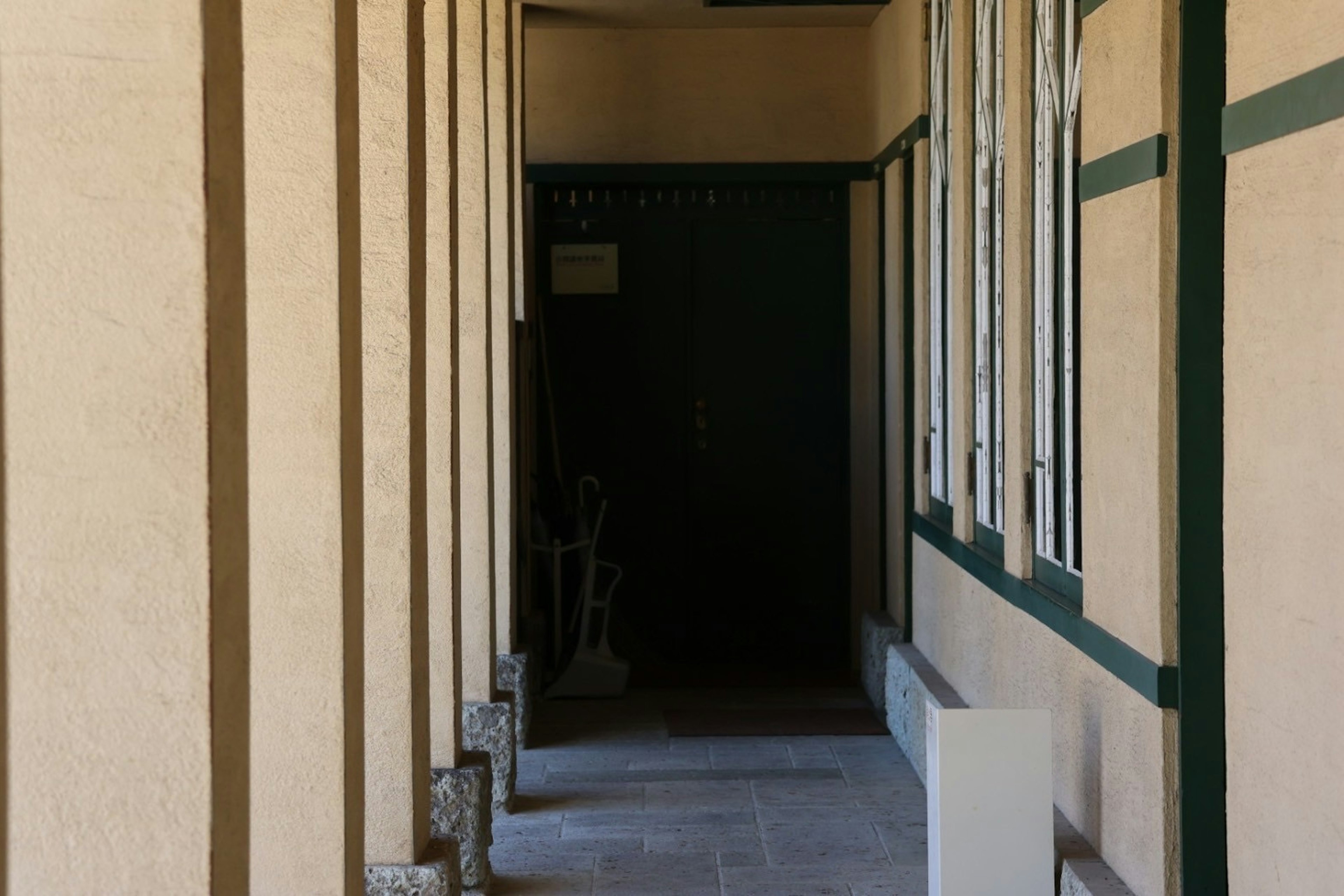 Long corridor with light-colored walls and green-framed windows