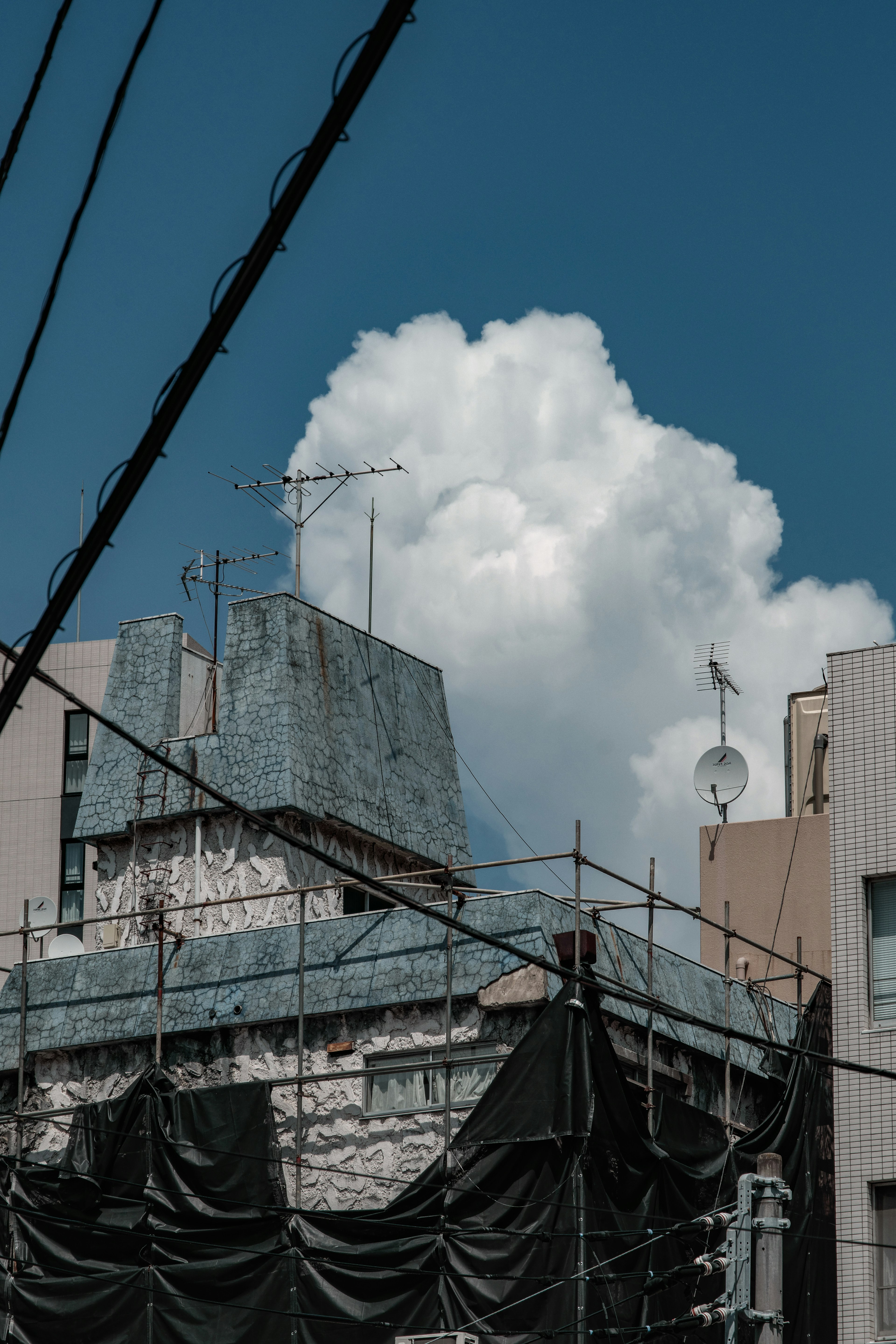 青い空に白い雲が浮かぶ都市のビルの屋上と工事現場