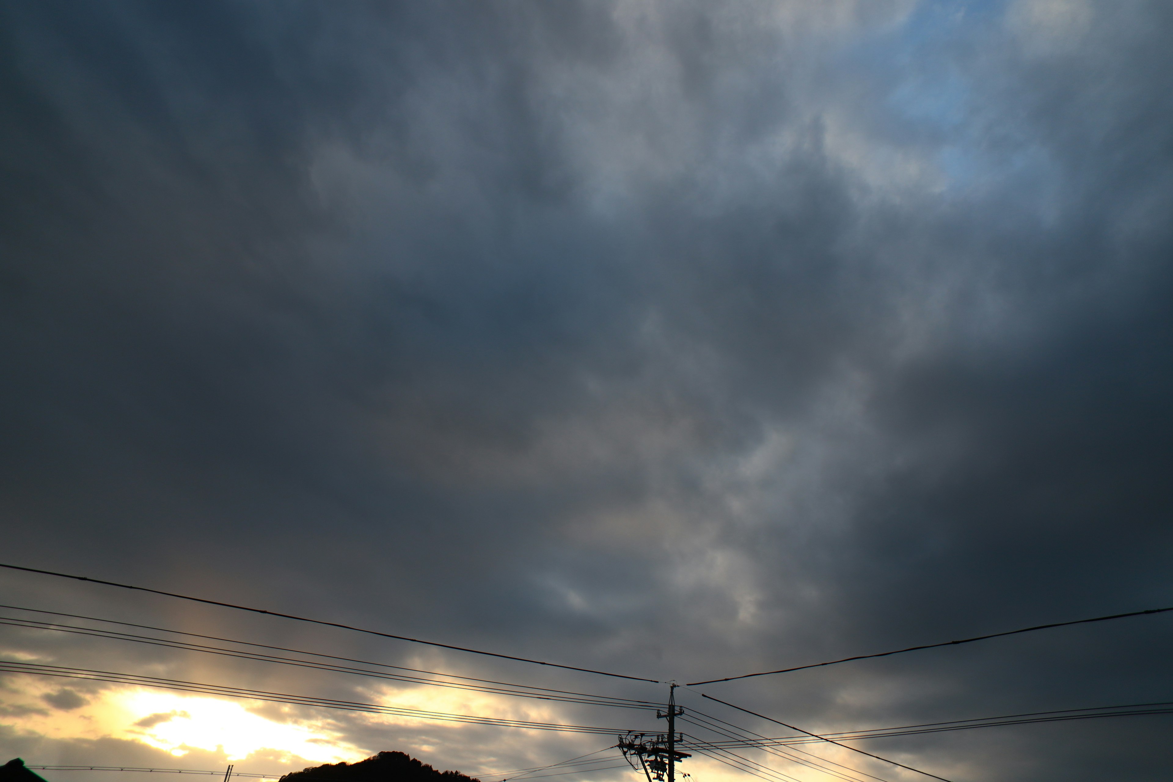 暗い雲が広がる空と微かな夕日